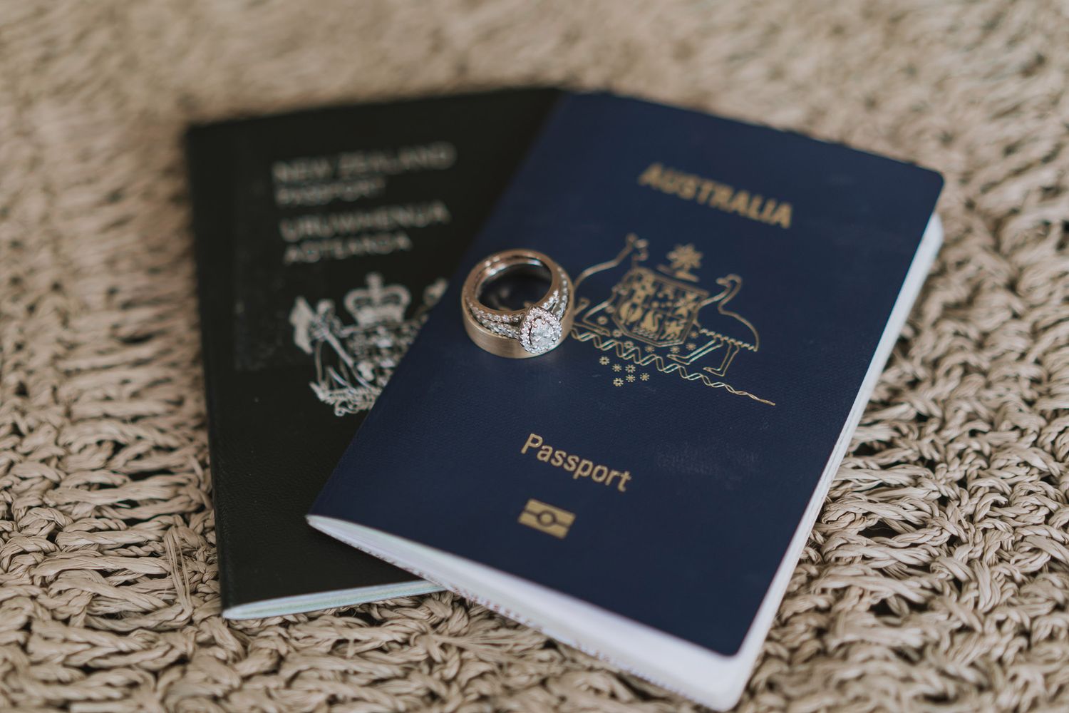 Australian passport and wedding ring placed on top of another passport against a textured carpet background.