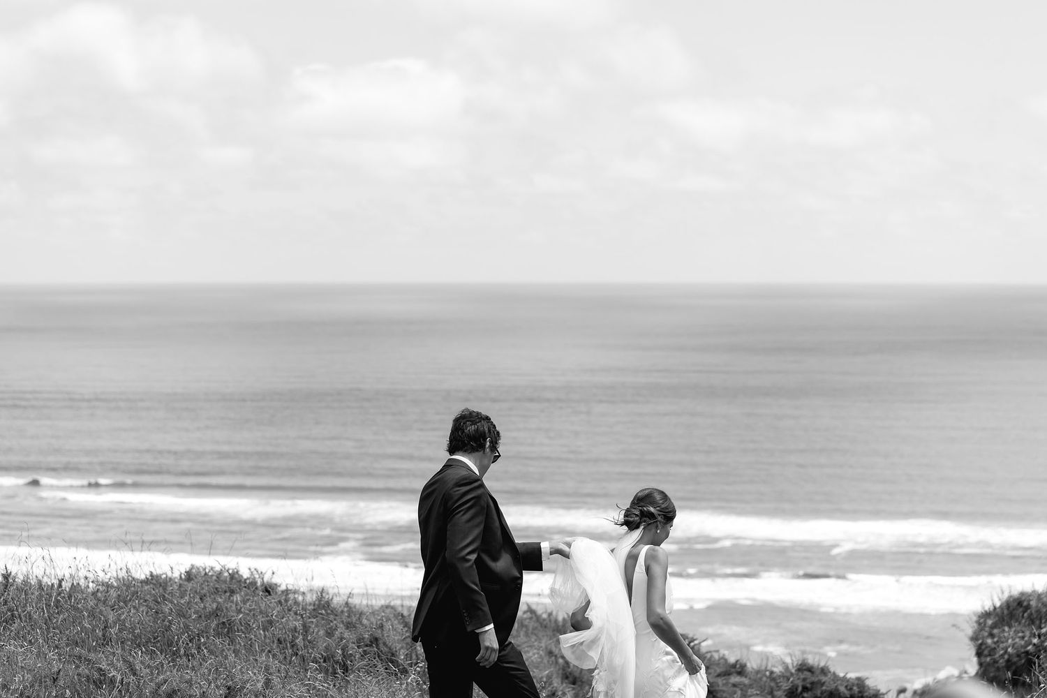 A loving couple shares an intimate moment while overlooking a scenic coastal landscape at sunset.