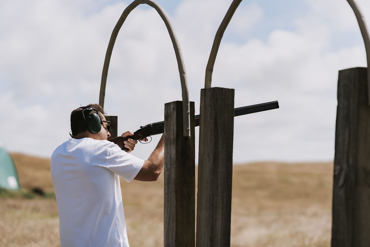 Two people shoot targets at an outdoor rifle range in a desert setting.