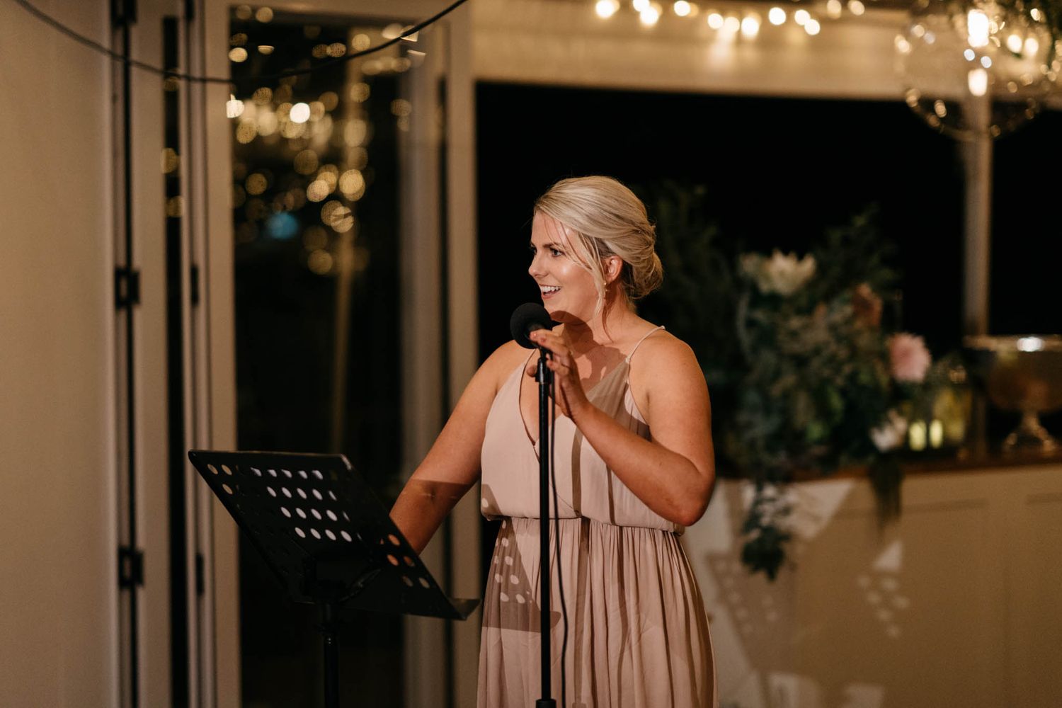 A romantic evening wedding reception setup with string lights creating a warm ambiance under a covered outdoor venue.
