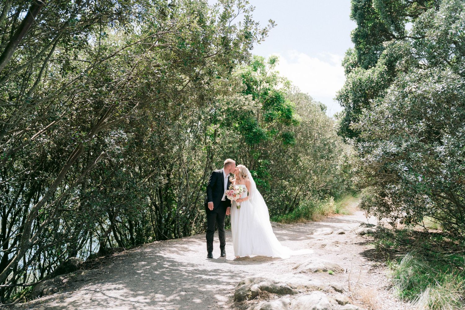 Tree-lined pathway creates a natural backdrop for elegant outdoor wedding photography.