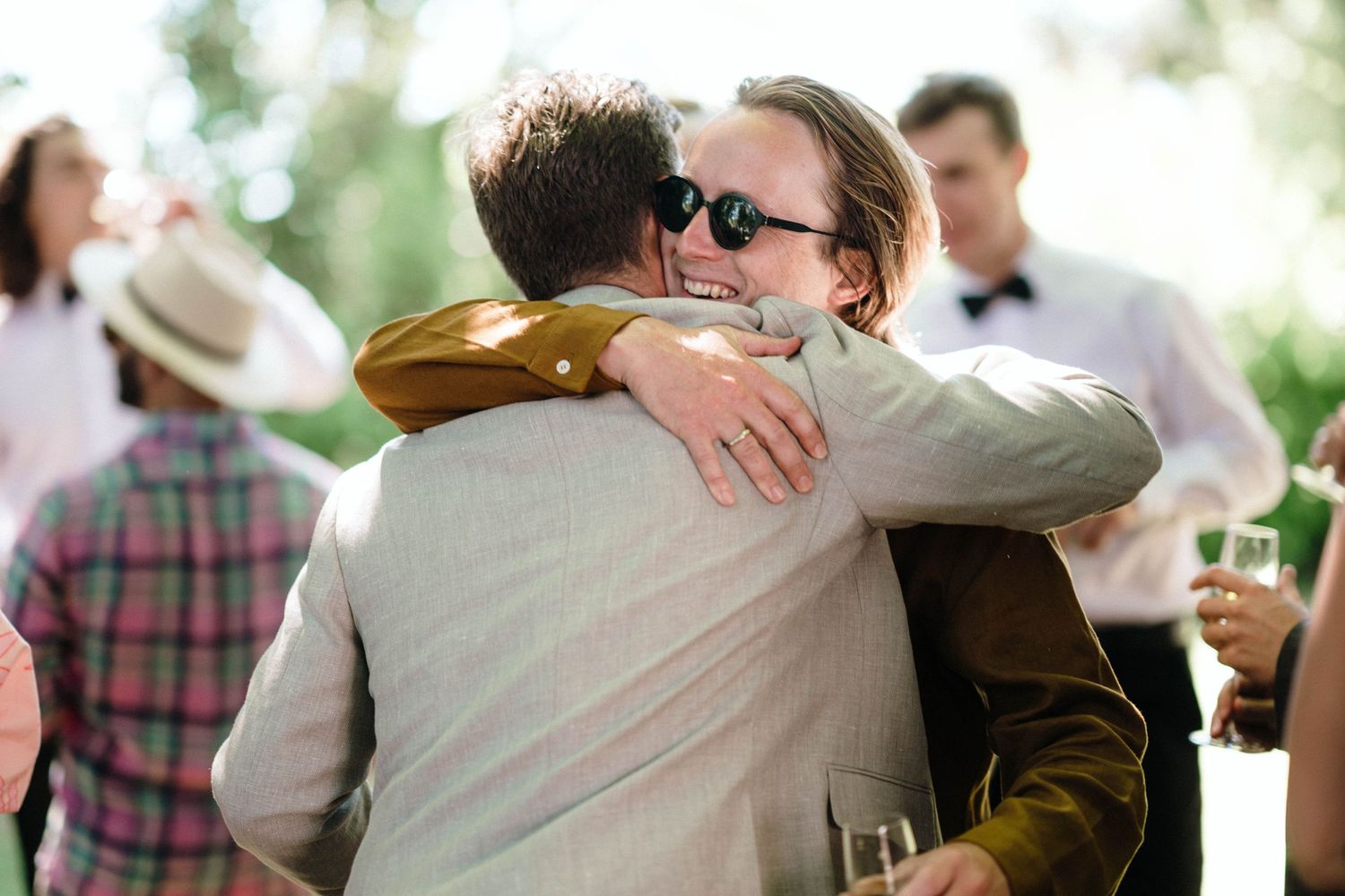 Two guests sharing an emotional embrace at an outdoor celebration.