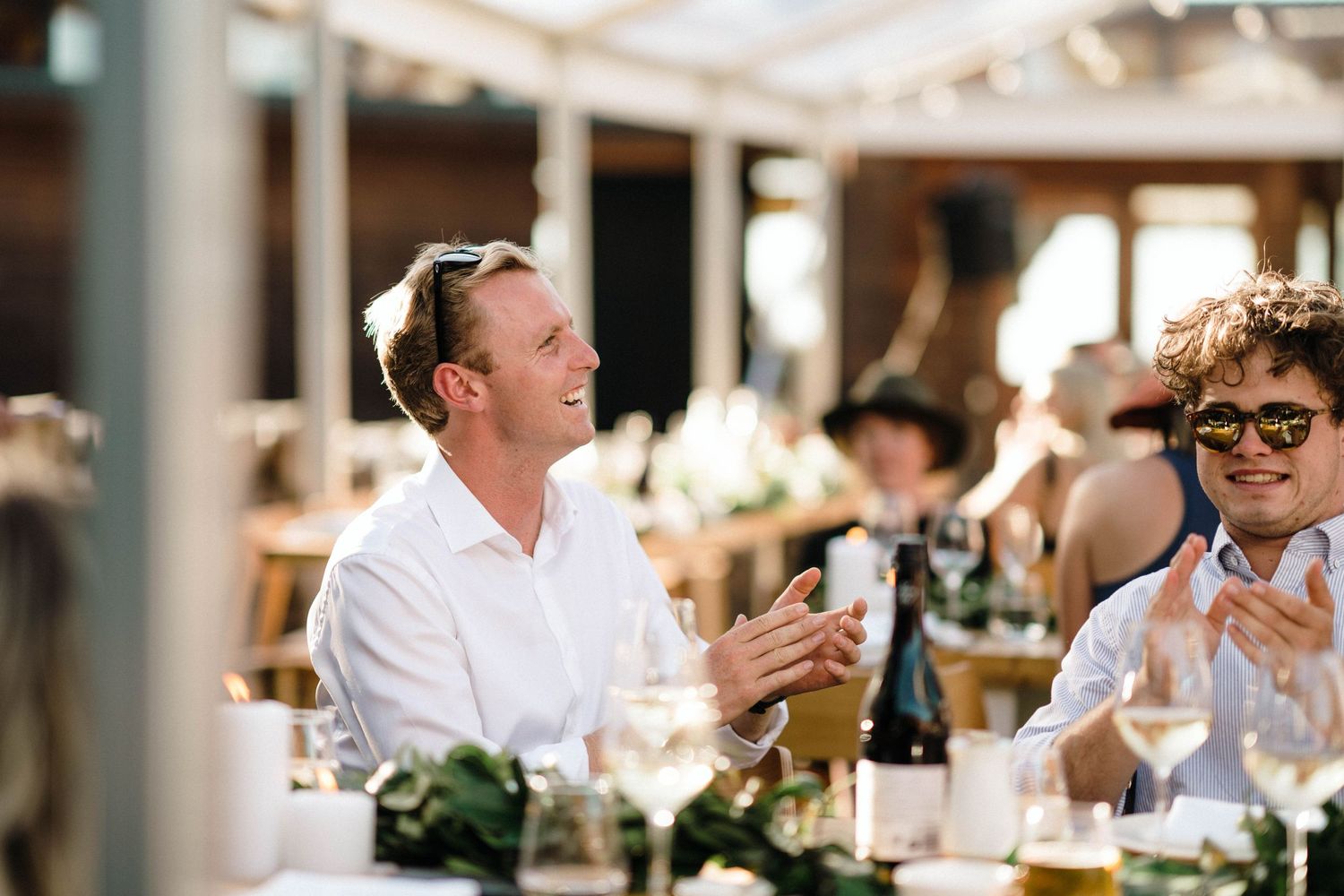 Wedding guests enjoying a celebration and applauding during an outdoor reception.