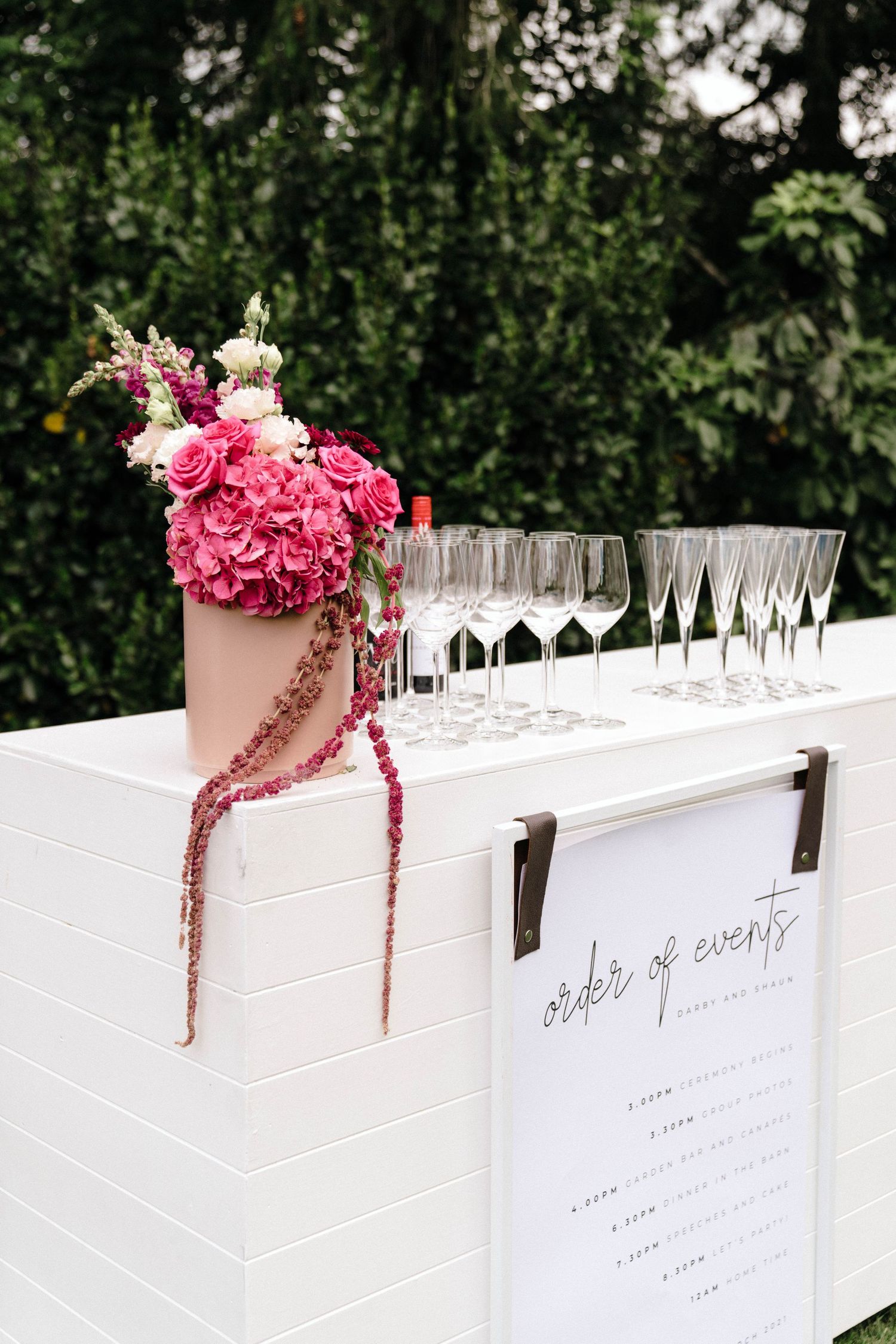 White seating cards and wine glasses line an elegant table with pink floral arrangements.