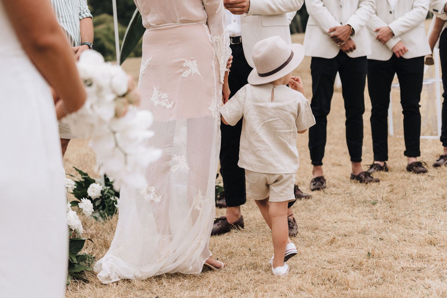 Wedding party members walking through a grassy outdoor venue in elegant attire.