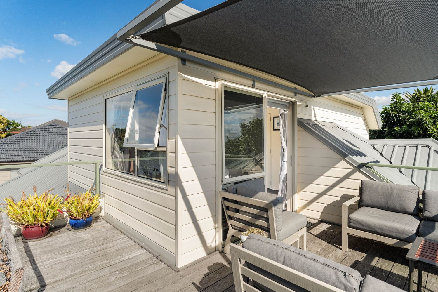 Contemporary deck area with wooden flooring, rocking chairs, and outdoor seating under a covered overhang.