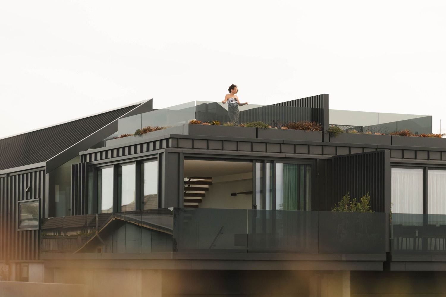 Modern dark architectural structure with large windows and geometric lines against a misty background.