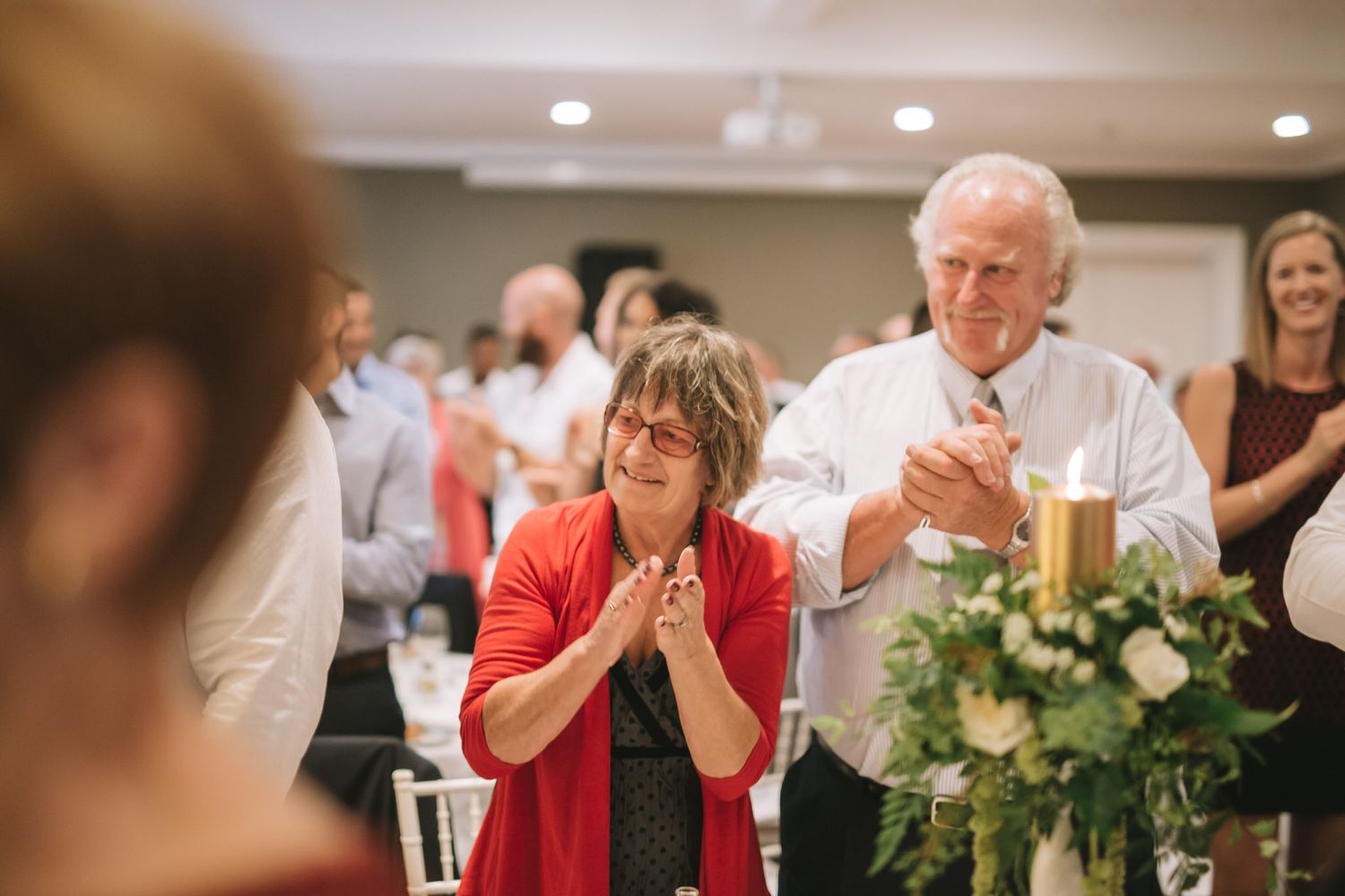Wedding guests showing emotional reactions during a reception celebration with floral decorations.