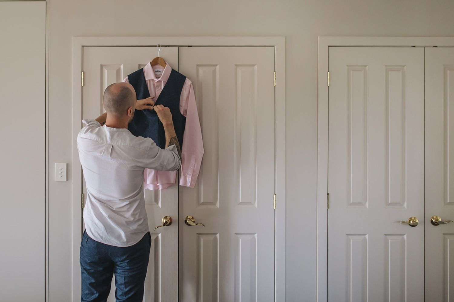 Someone hangs a pink blazer on a white closet door while getting ready.