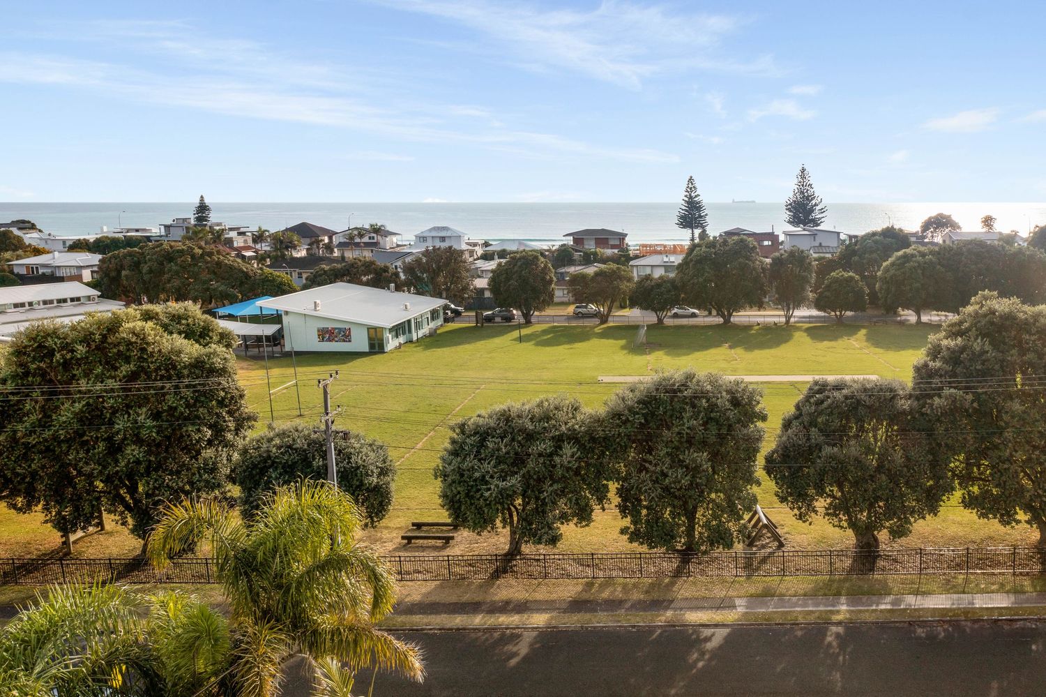 Scenic coastal landscape with green park slope leading down to waterfront homes and ocean views.