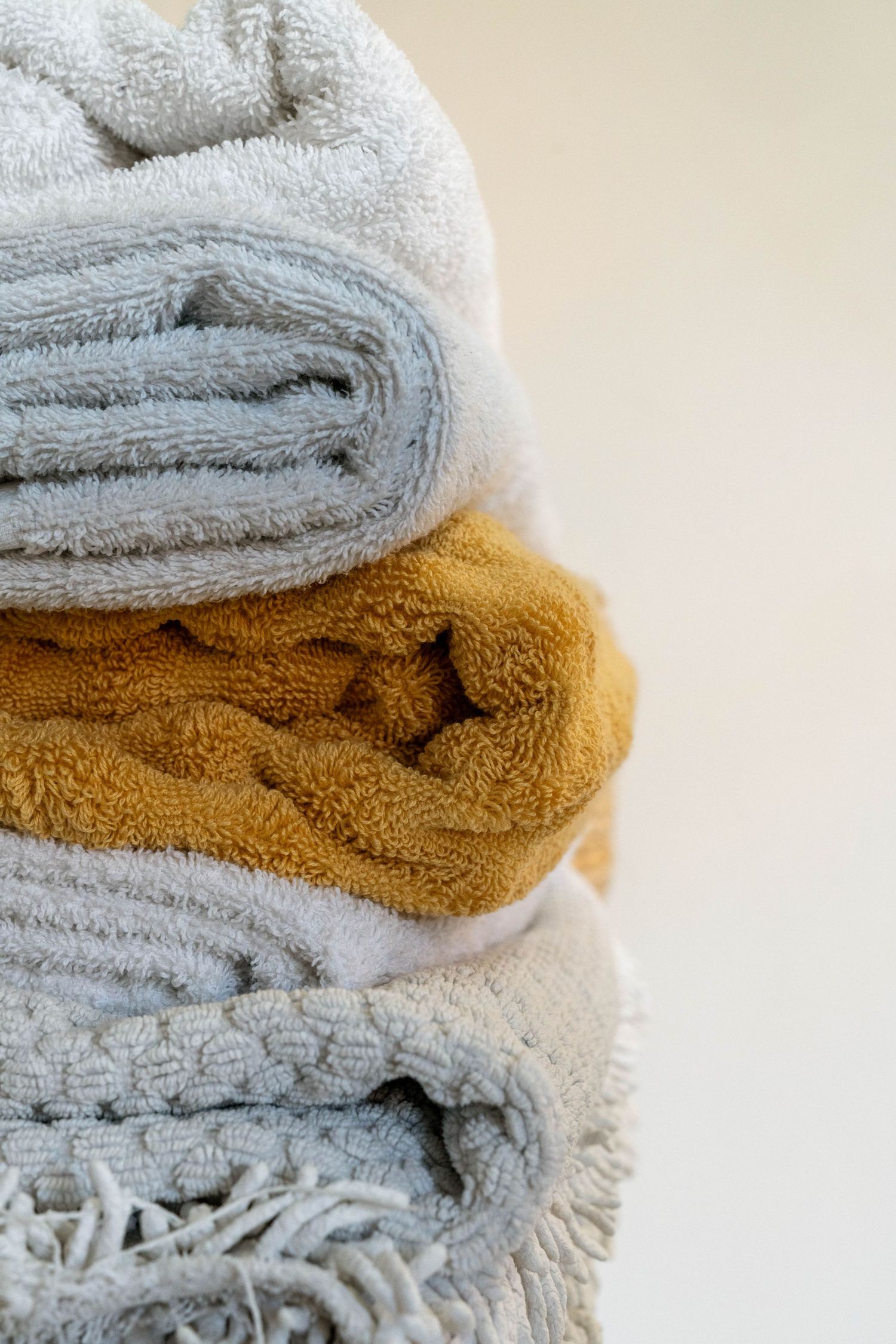 Stack of folded towels in grey and mustard colors showing soft texture detail.