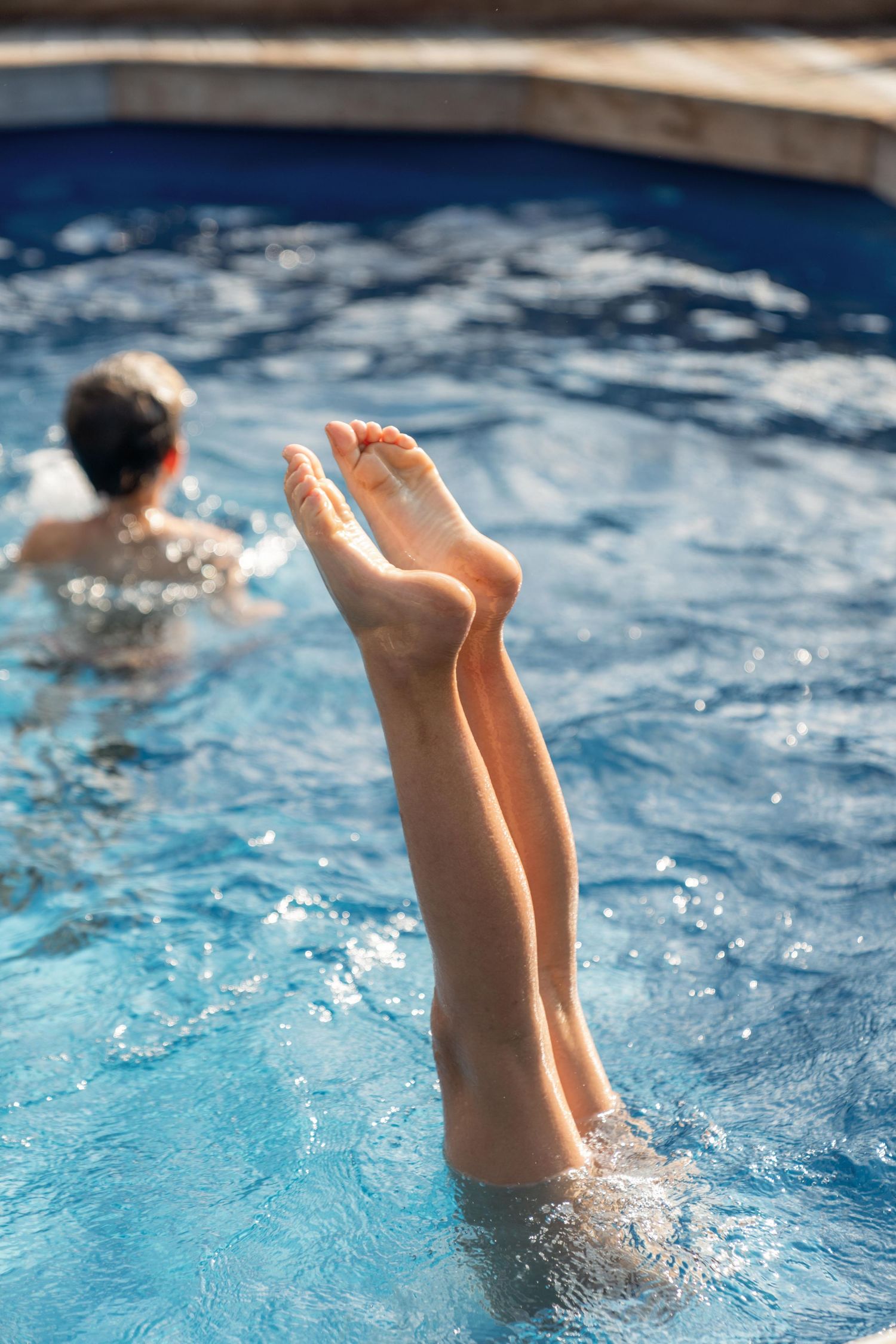 Playful splashing and feet kicking up from a blue swimming pool during an energetic swim.
