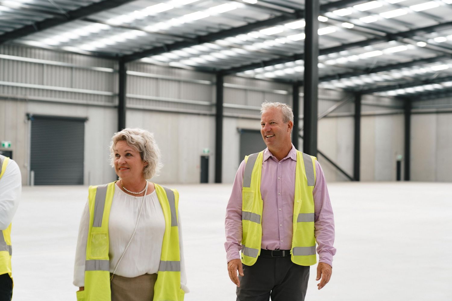 Team members wearing safety vests inspect an industrial warehouse facility.