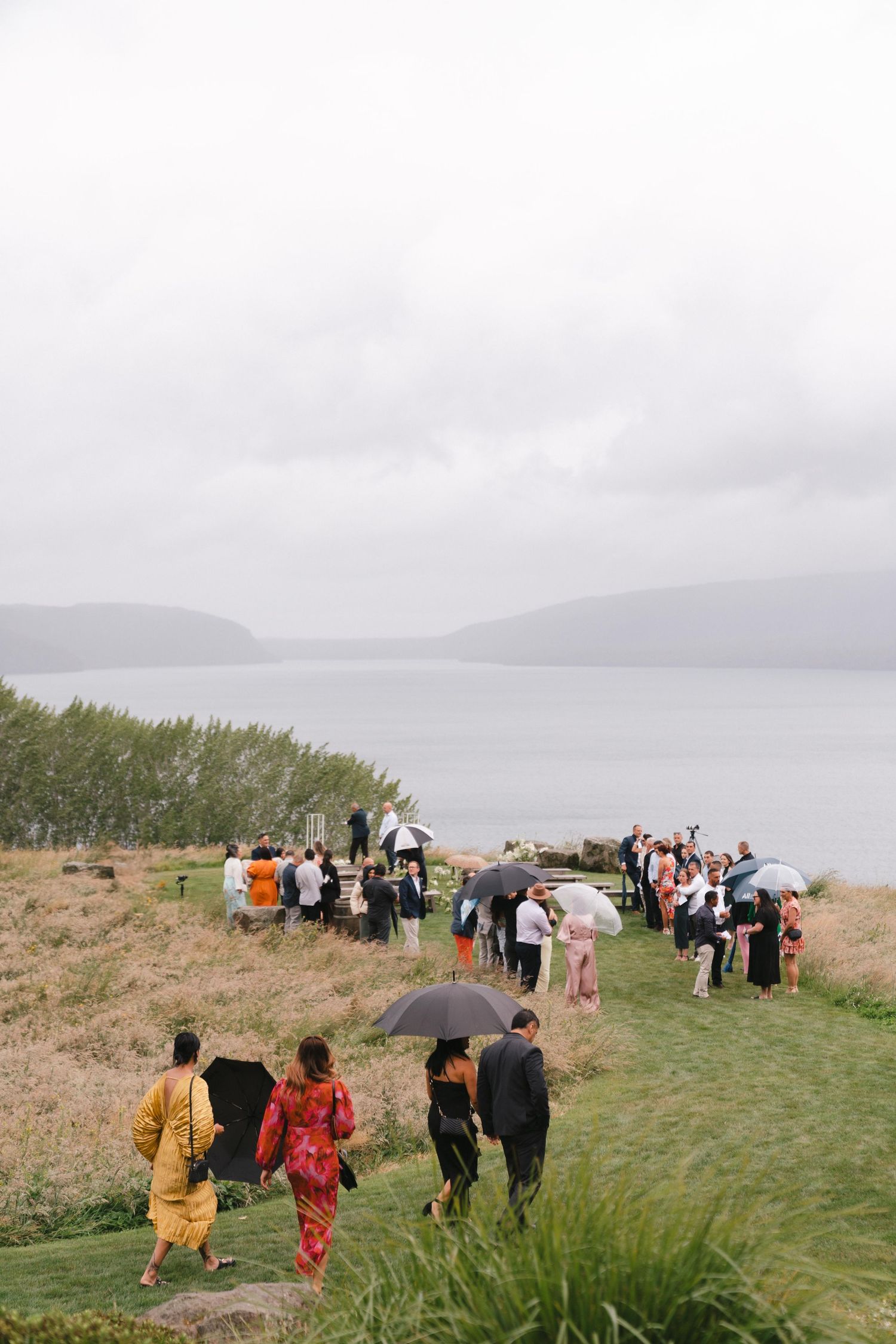 Wedding guests walking down a coastal path towards ceremony site with ocean views.