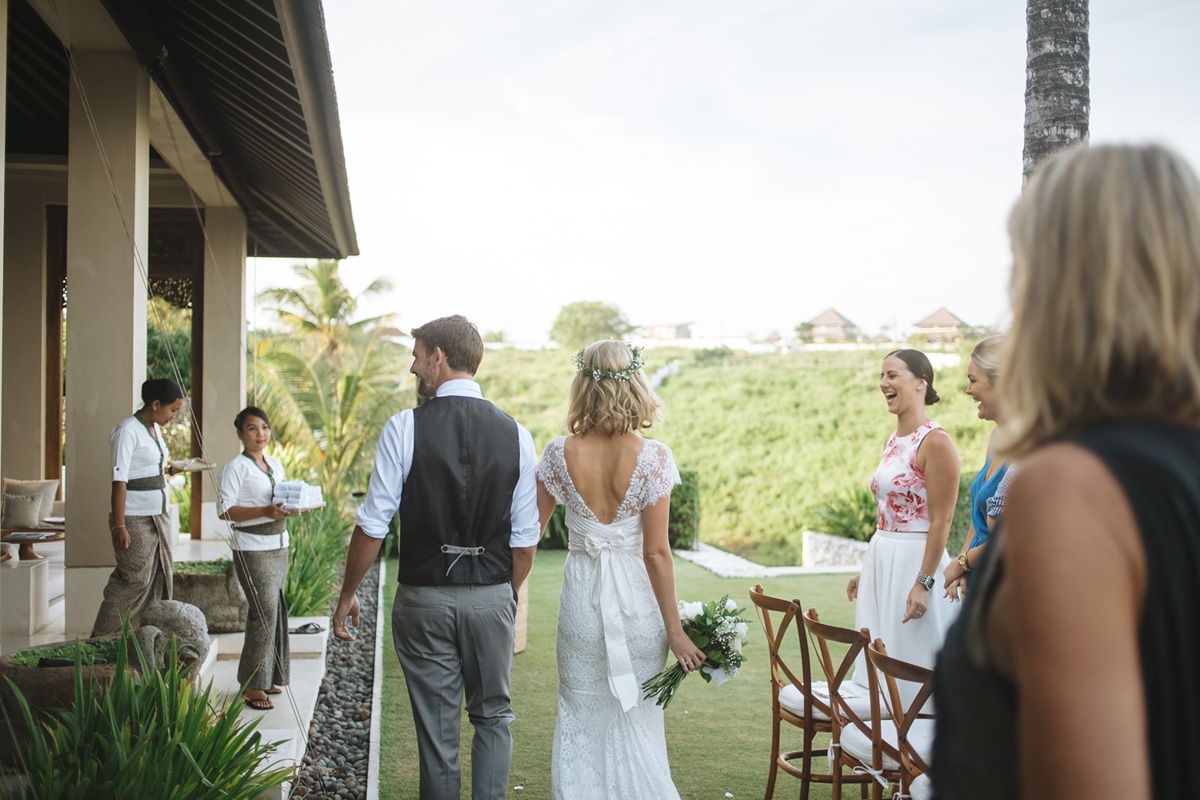 Small wedding gathering on an outdoor patio overlooking scenic green fields on a sunny afternoon.