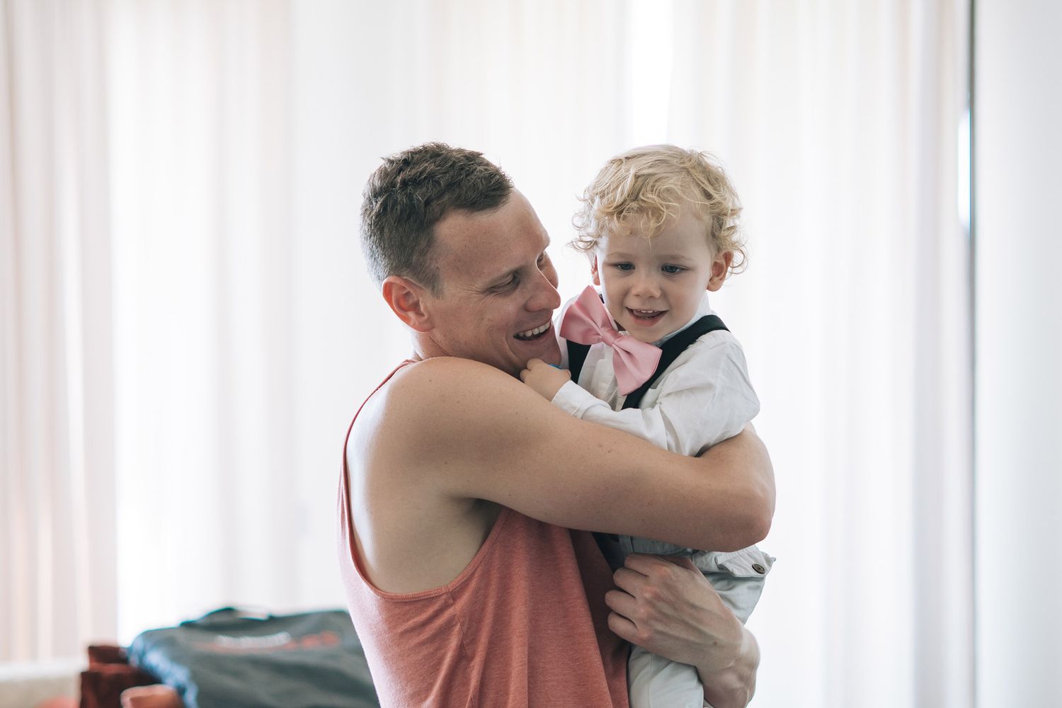Family members embracing and sharing tender moments in a bright room with white curtains.