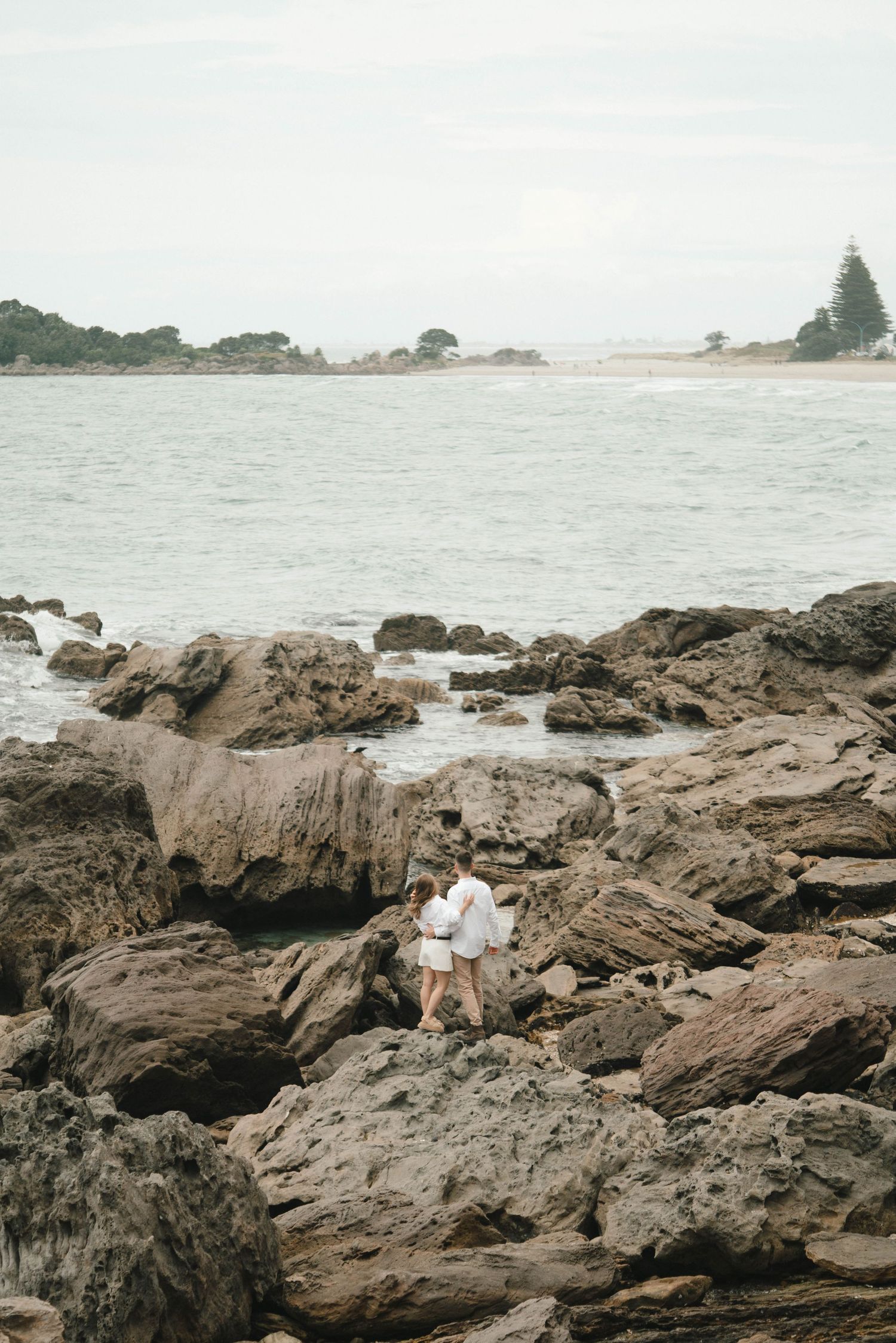 Rugged rocky shoreline with ocean and coastal landscape in background.
