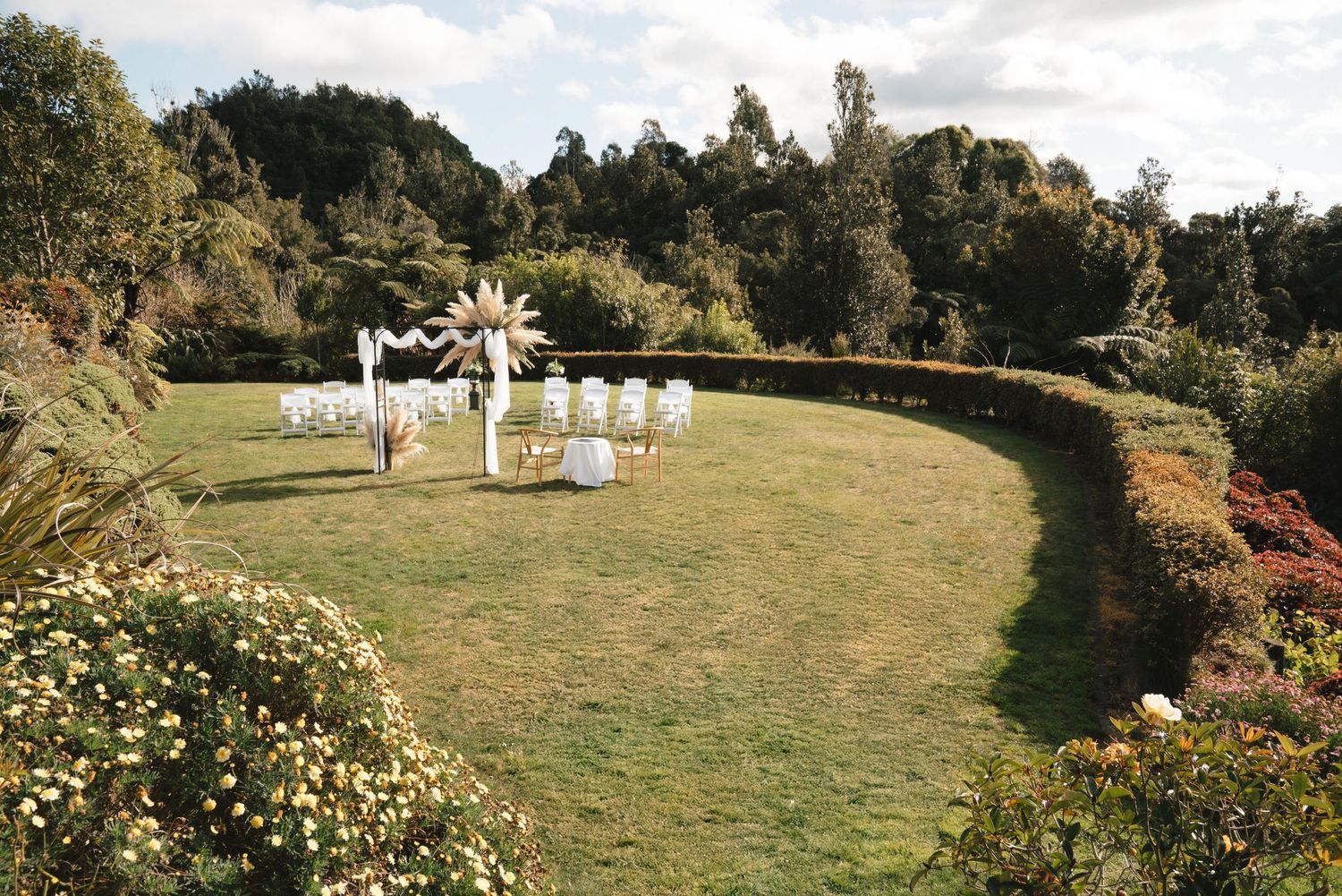 A serene outdoor wedding ceremony setup on a hillside with white chairs arranged in rows facing an altar.