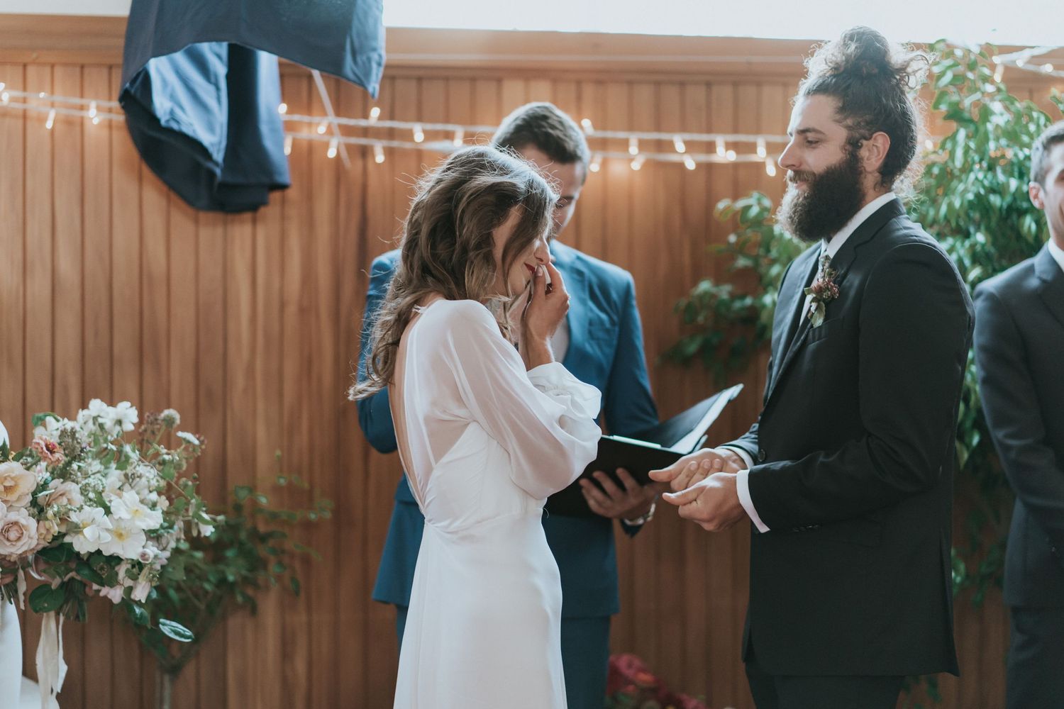 Outdoor wedding ceremony taking place in a backyard with wooden fence and floral arrangements.