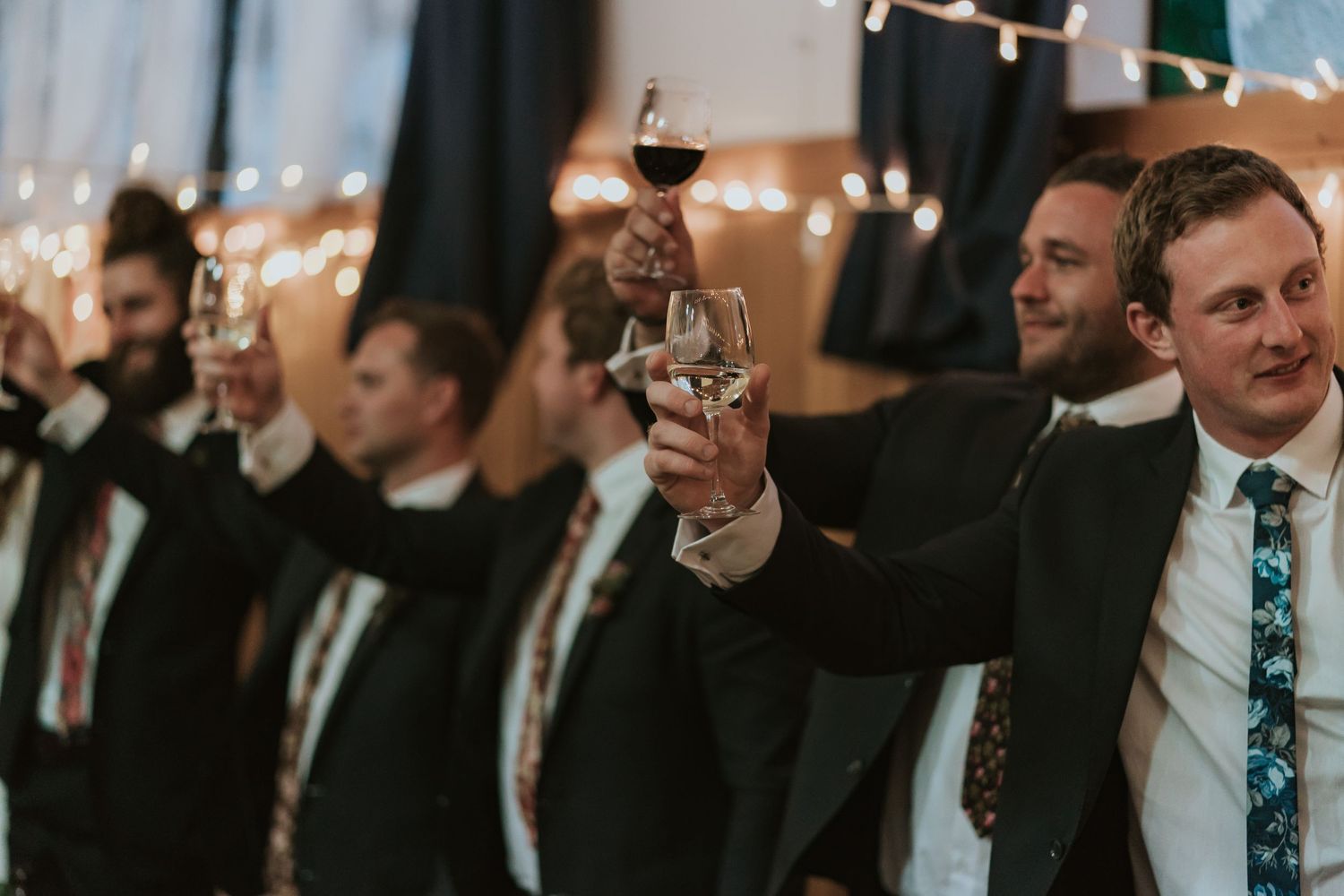 Well-dressed people in dark suits raise glasses in a toast at an elegant celebration event.