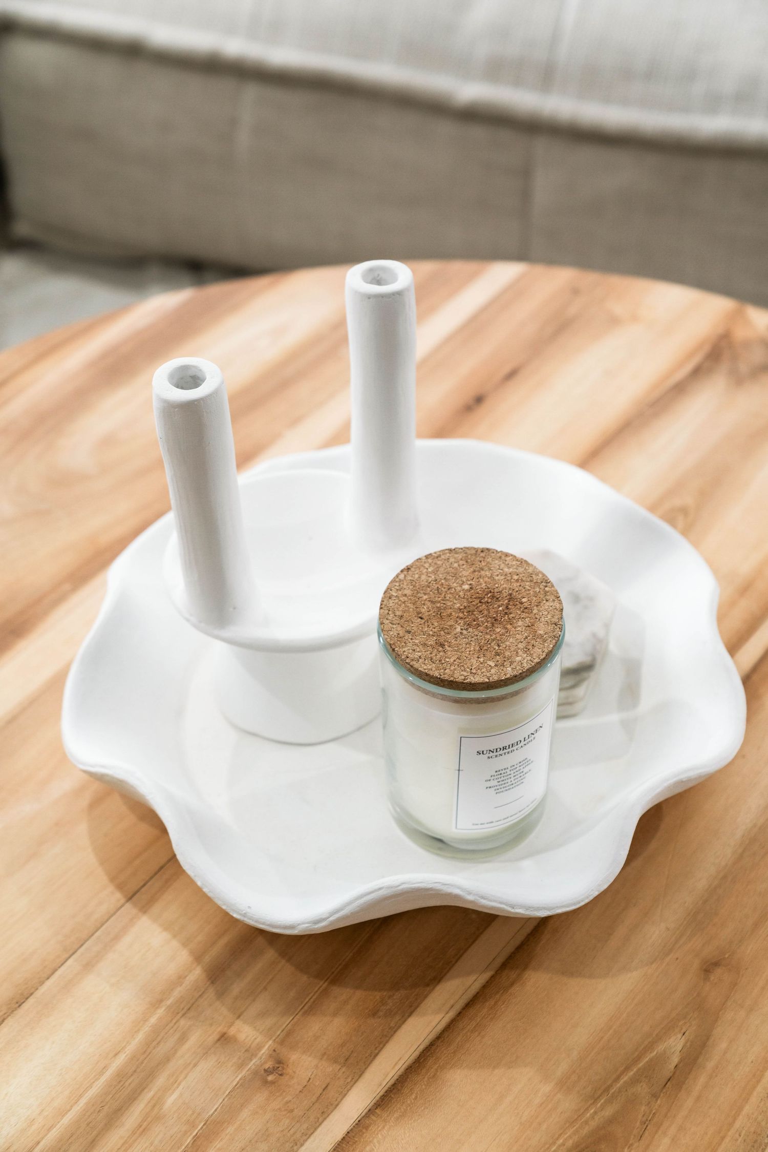 A series of white minimalist candle holders with curved organic shapes displayed on a wooden surface with a small jar.