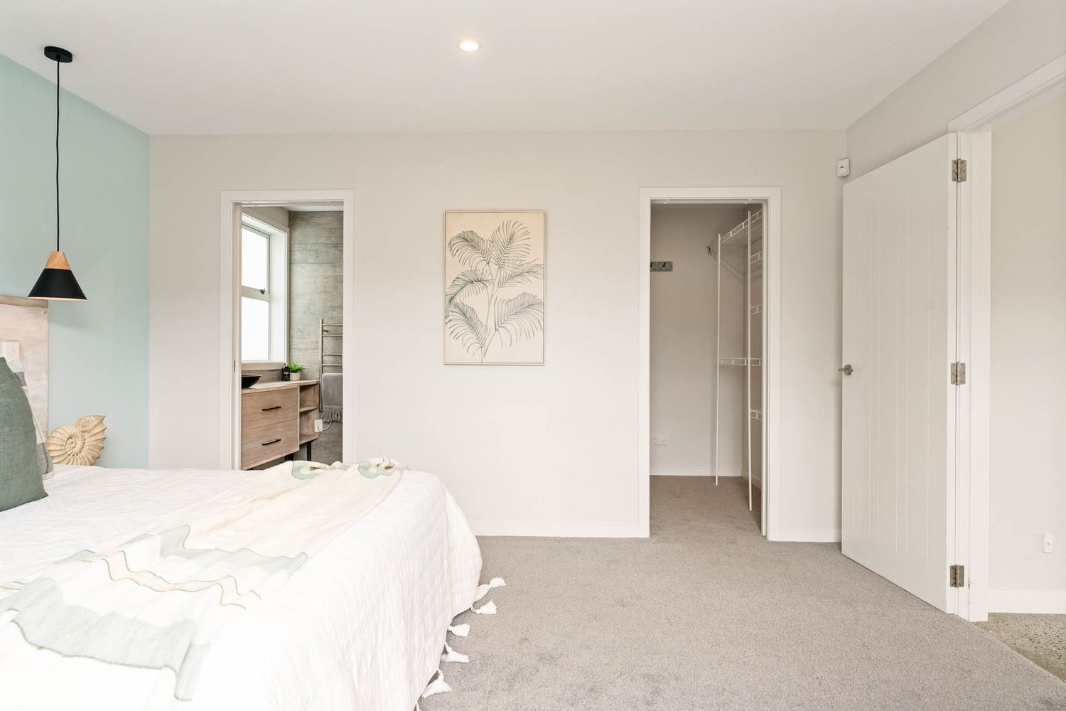 Minimalist bedroom with light mint walls, pendant lamp, and white bedding.