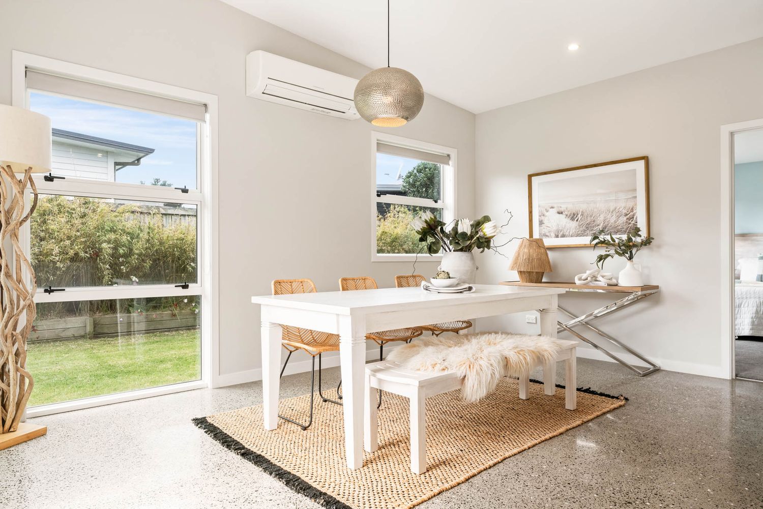 Modern open-plan living space with white walls, pendant lighting and natural light streaming through windows.