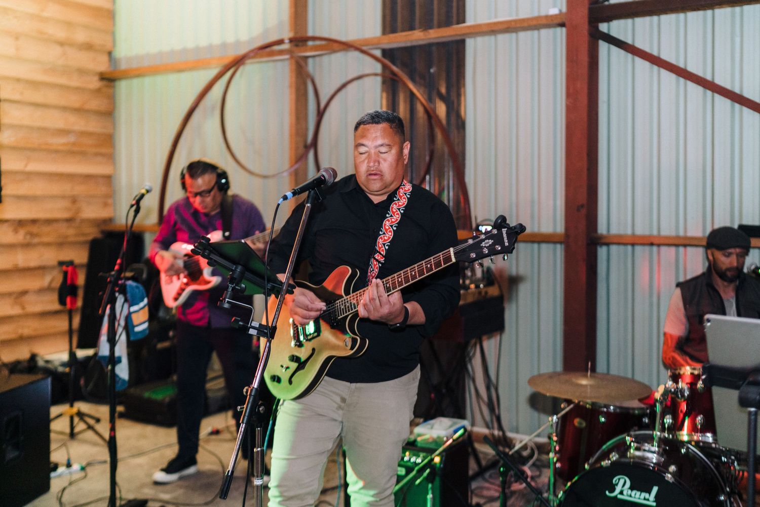 Musicians perform with guitars at a rustic wedding reception venue.
