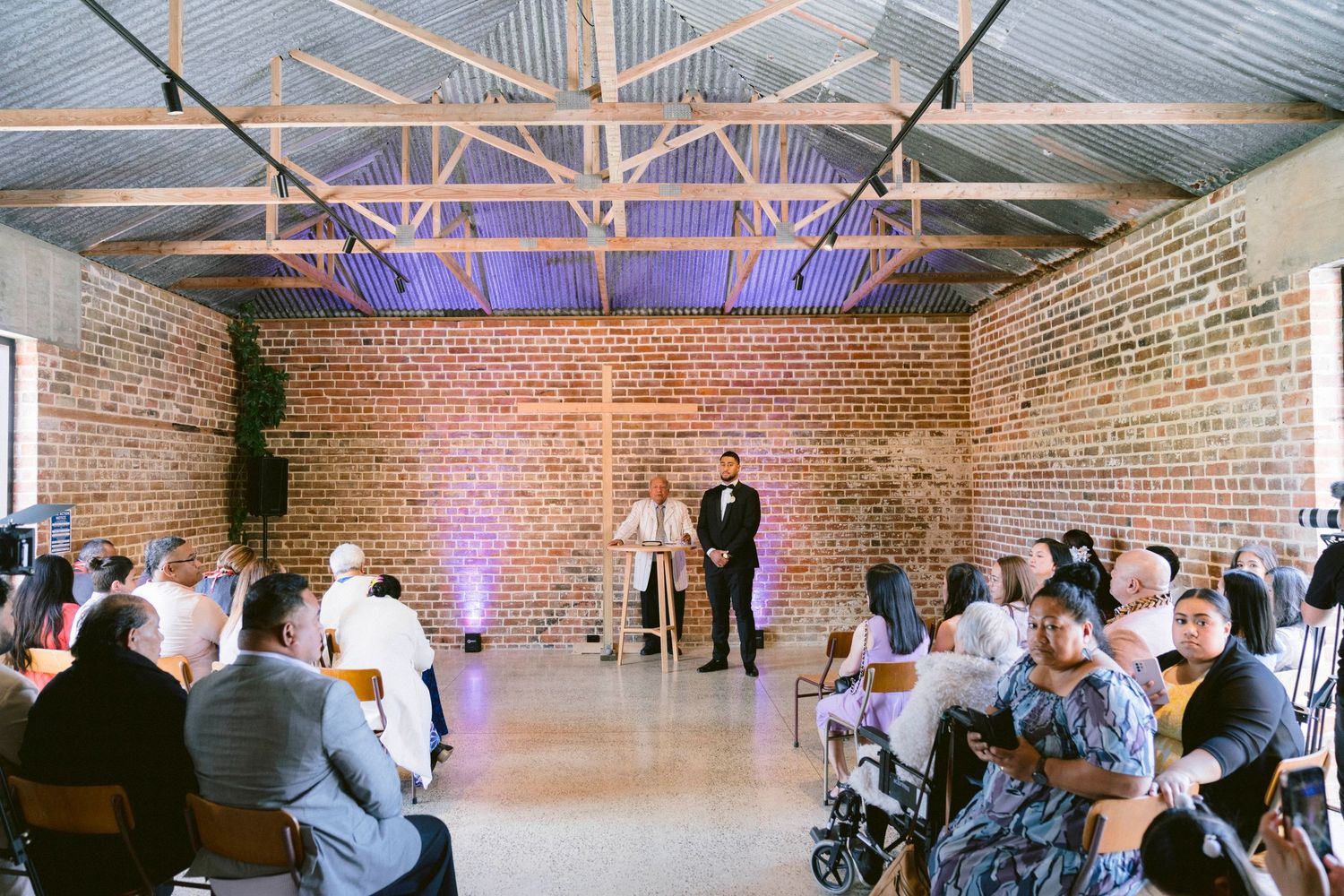 Wedding reception venue with exposed brick walls and purple uplighting.