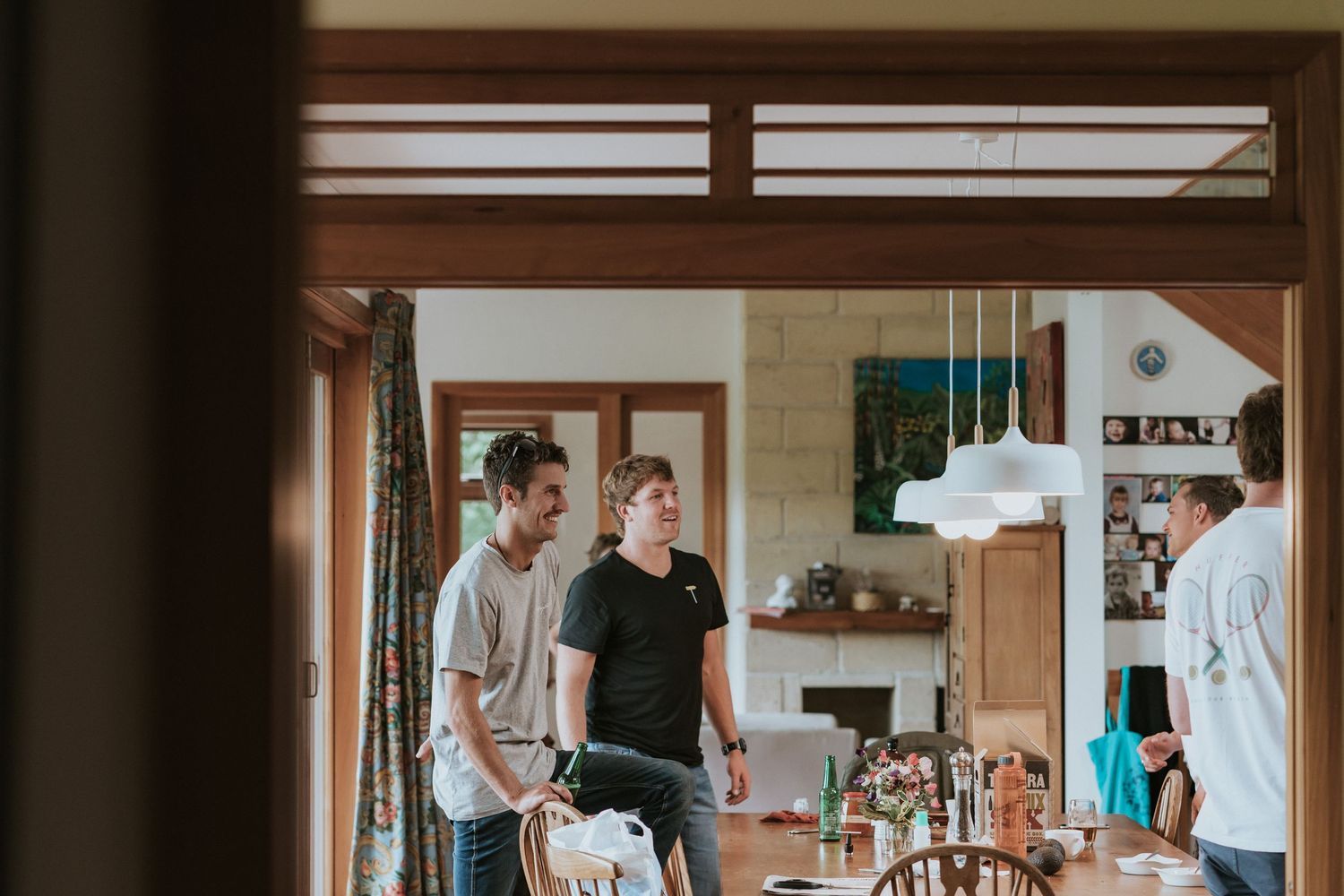 People gathering in a modern open concept kitchen and dining area with natural lighting.