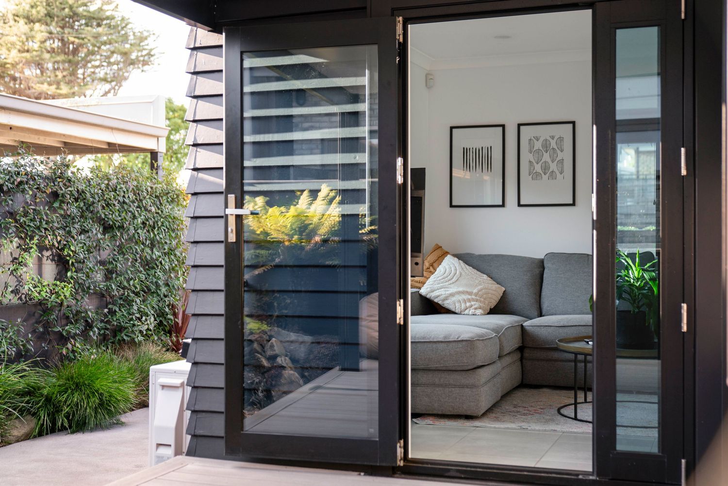 Contemporary living space with floor-to-ceiling glass doors and outdoor patio views.