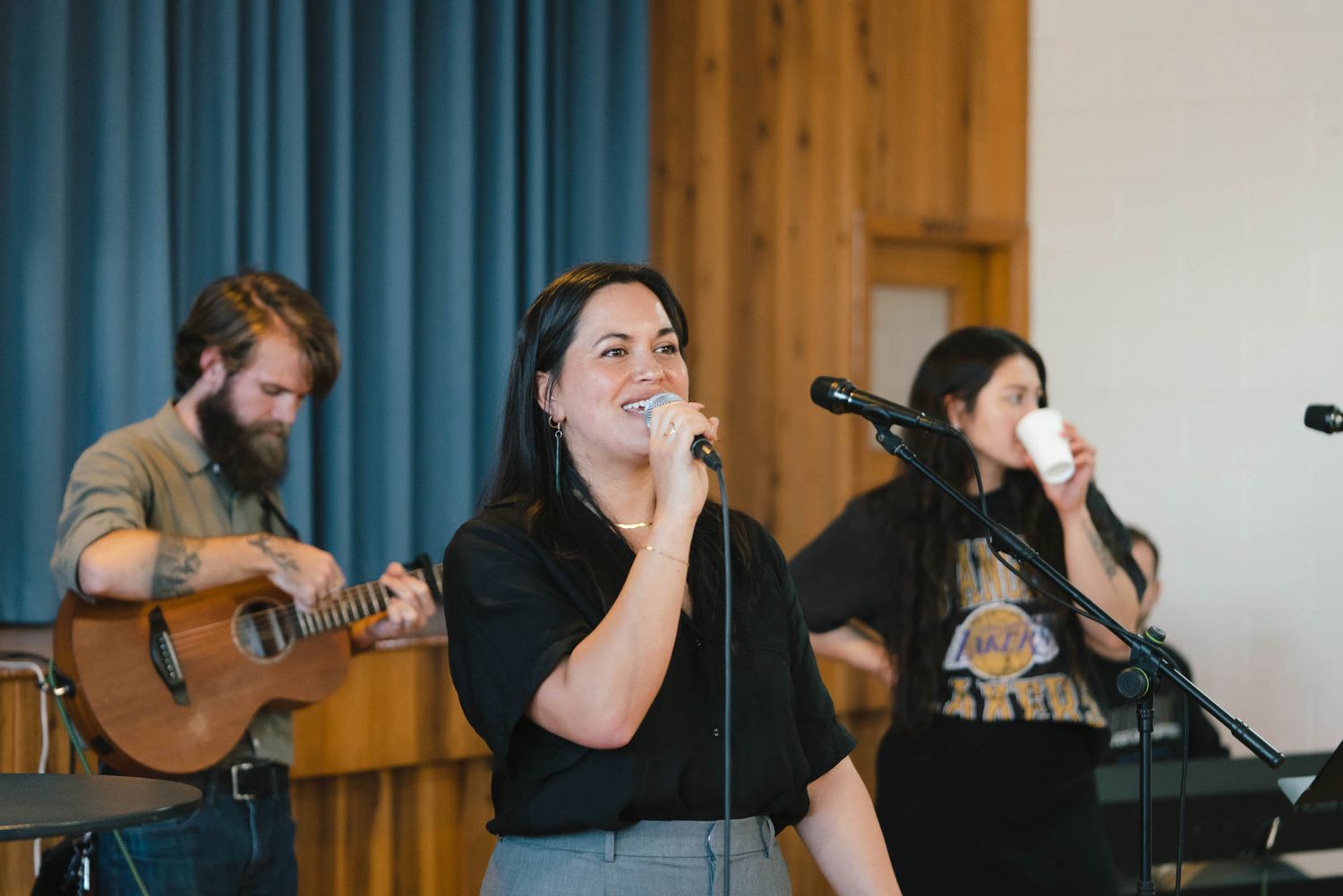 Musicians performing on stage with guitar and microphones in a church setting.