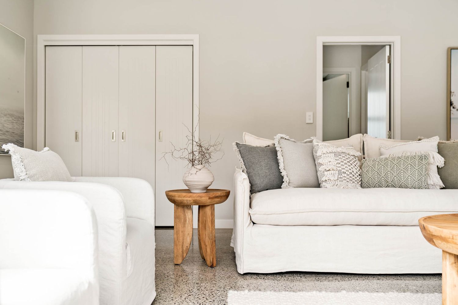 Clean modern living room with white slipcovered sofa, wooden side table, and neutral coastal-inspired decor.