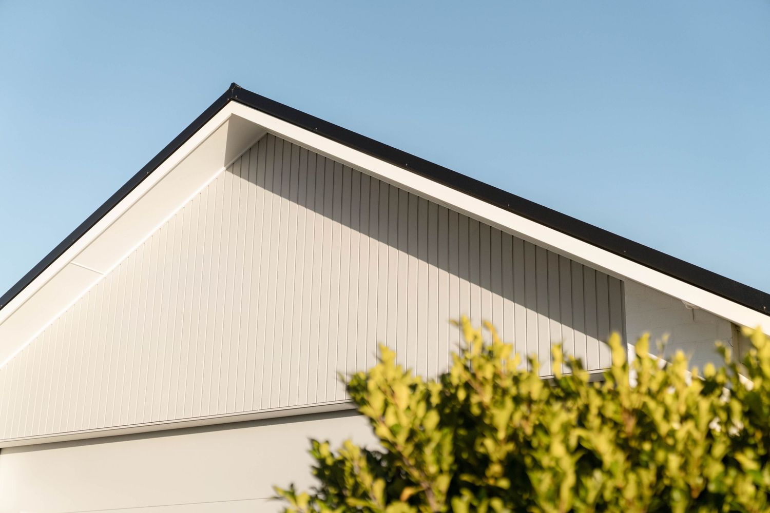 Close-up exterior view of white modern house roof line against blue sky.