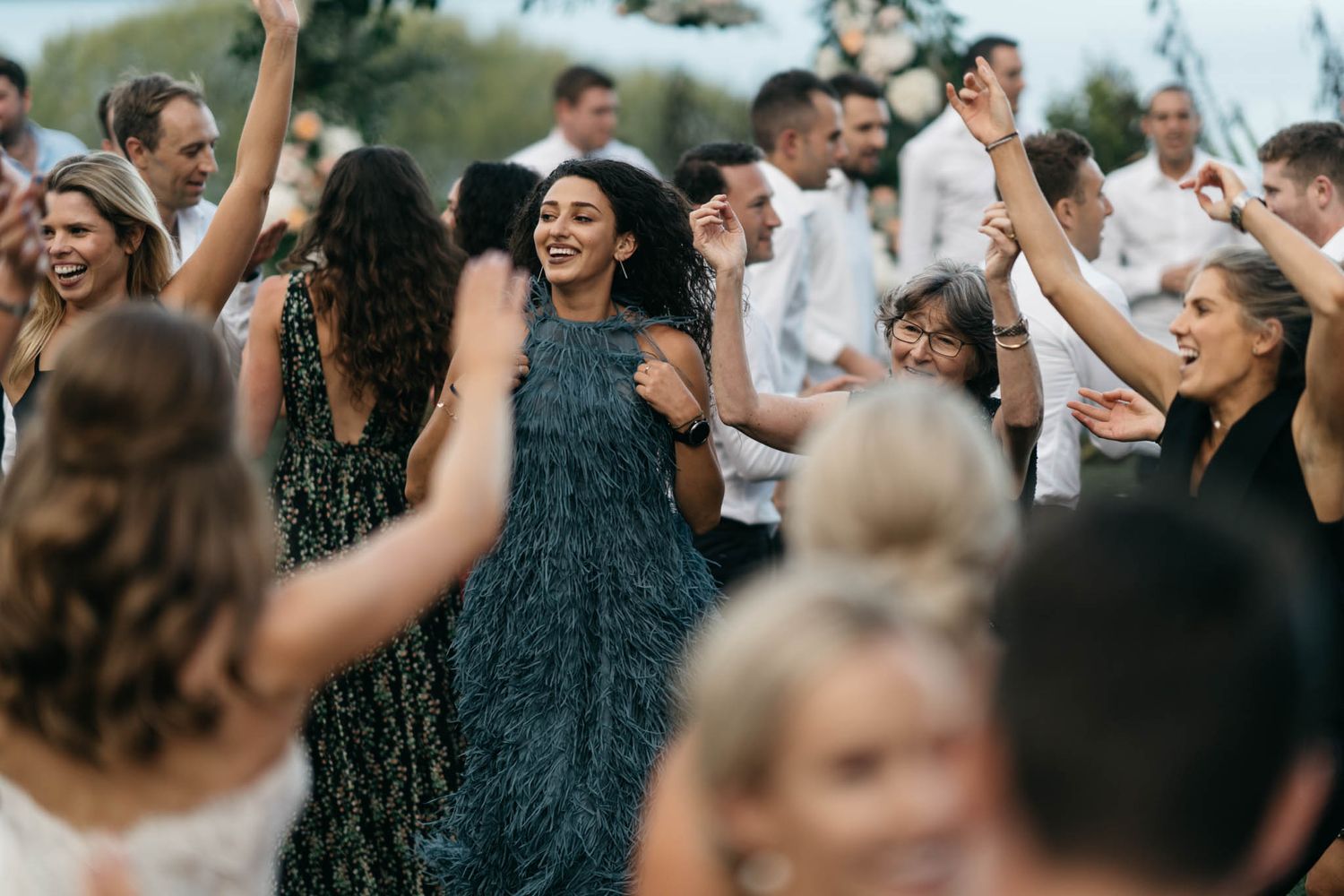 A large crowd of people dance with their arms raised during a celebration or party event.