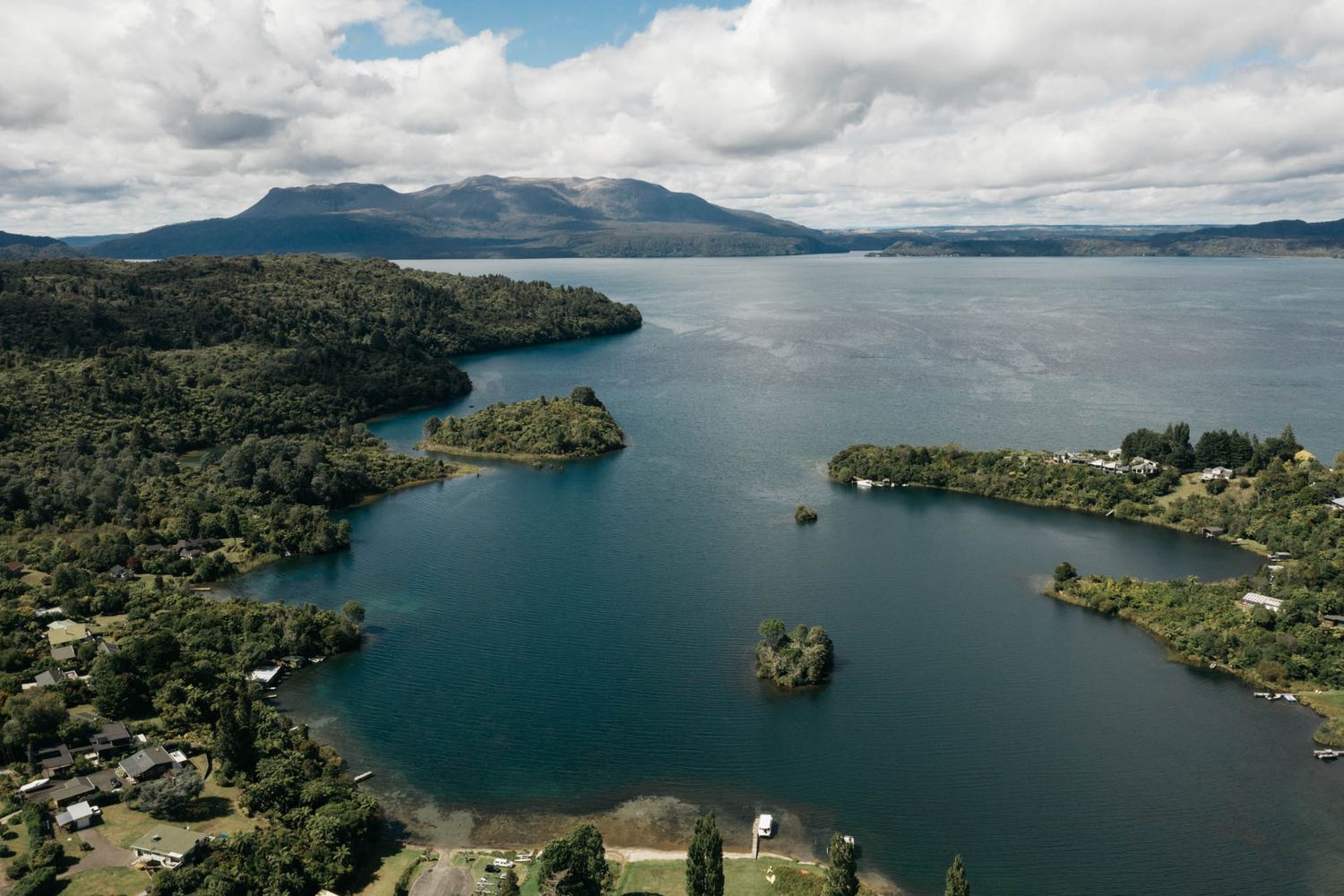Panoramic aerial views of Lake Taupo in New Zealand showing scenic bays, forested shores and crystal blue waters.