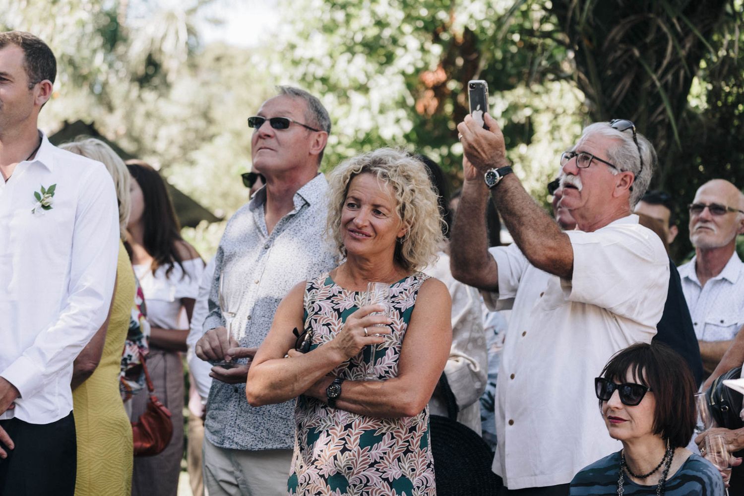 Wedding guests smile and celebrate outdoors during a joyful summer reception gathering.