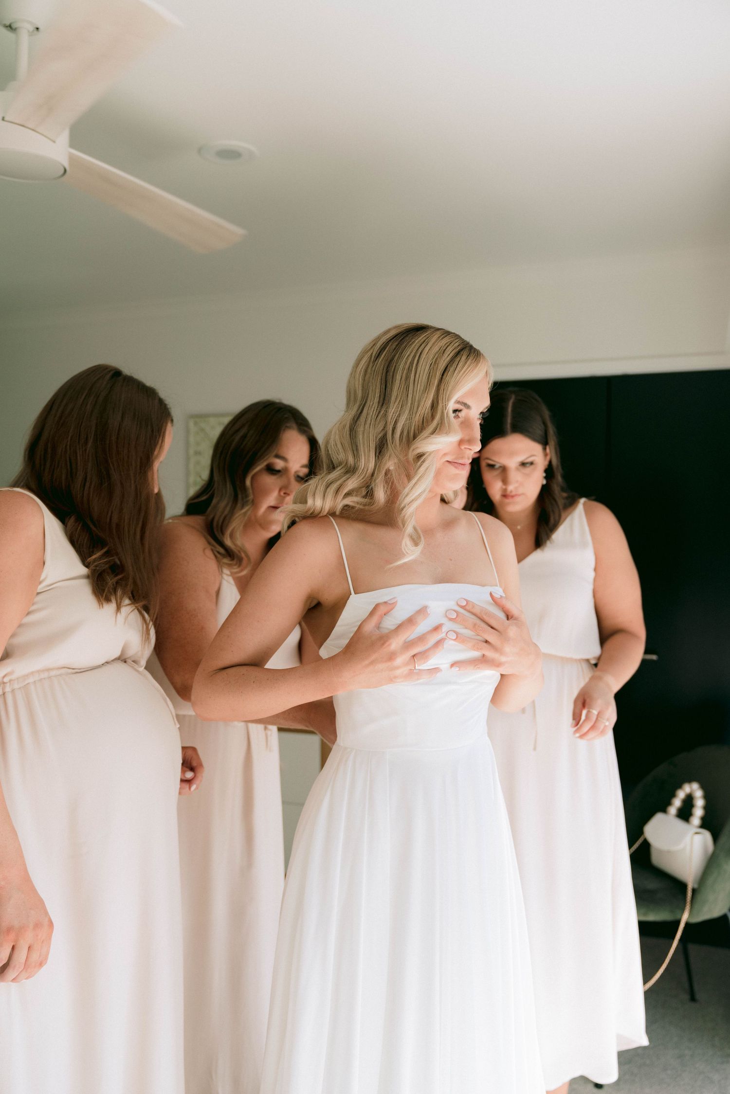 Bridesmaids in white dresses embracing in a group hug sequence.