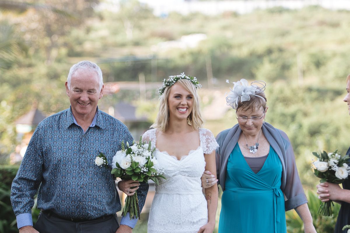 Wedding guests walking along a scenic outdoor path lined with lush greenery and palm trees.