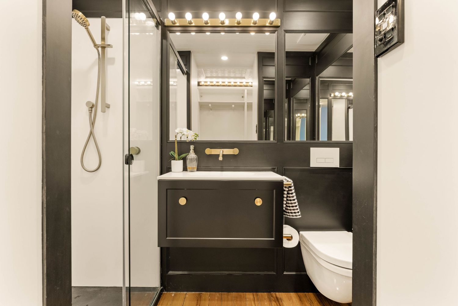 Modern bathroom interior with backlit mirror, floating vanity, and sleek black accents creating a luxurious ambiance.