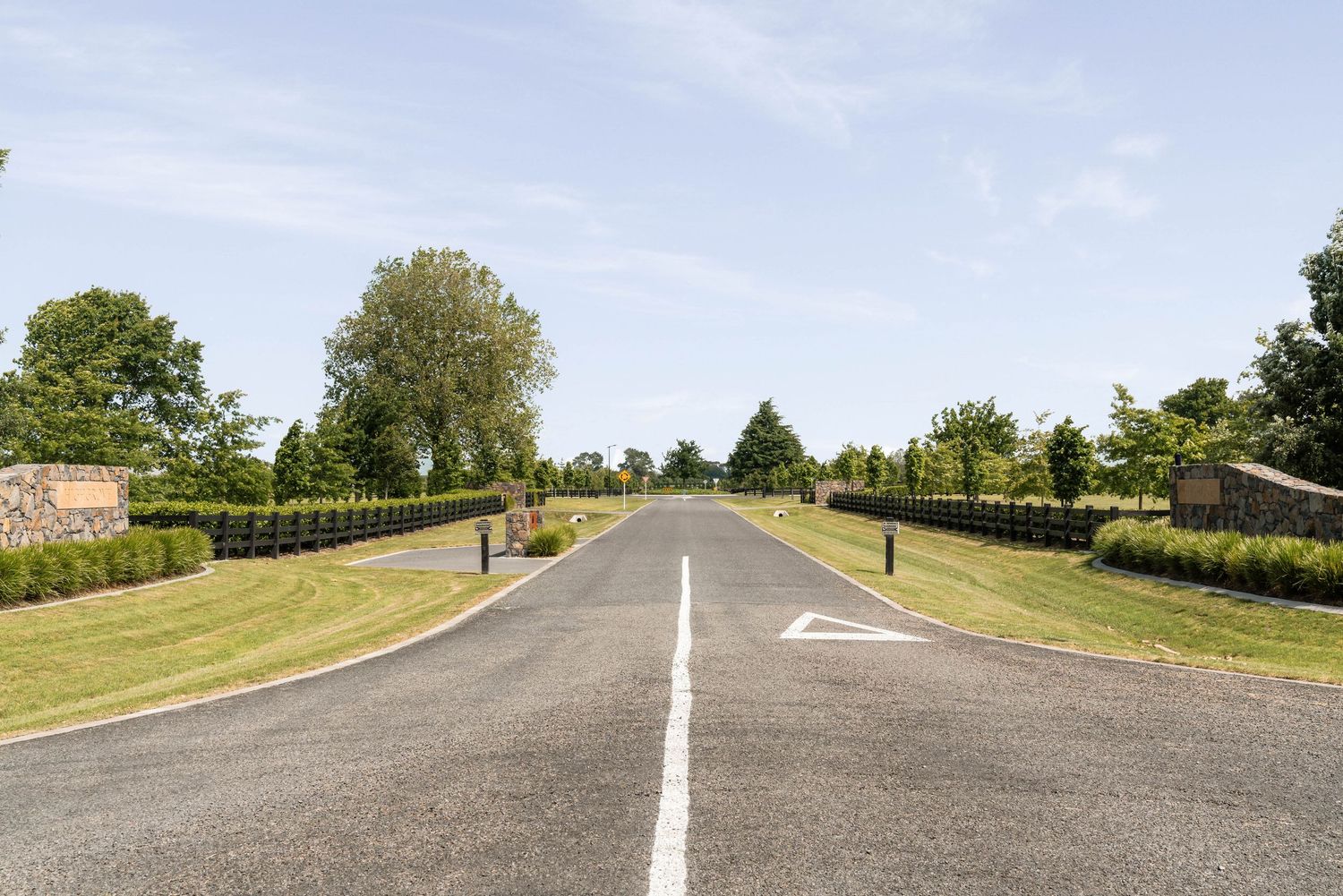 Wide paved road through rural countryside with white line markings.