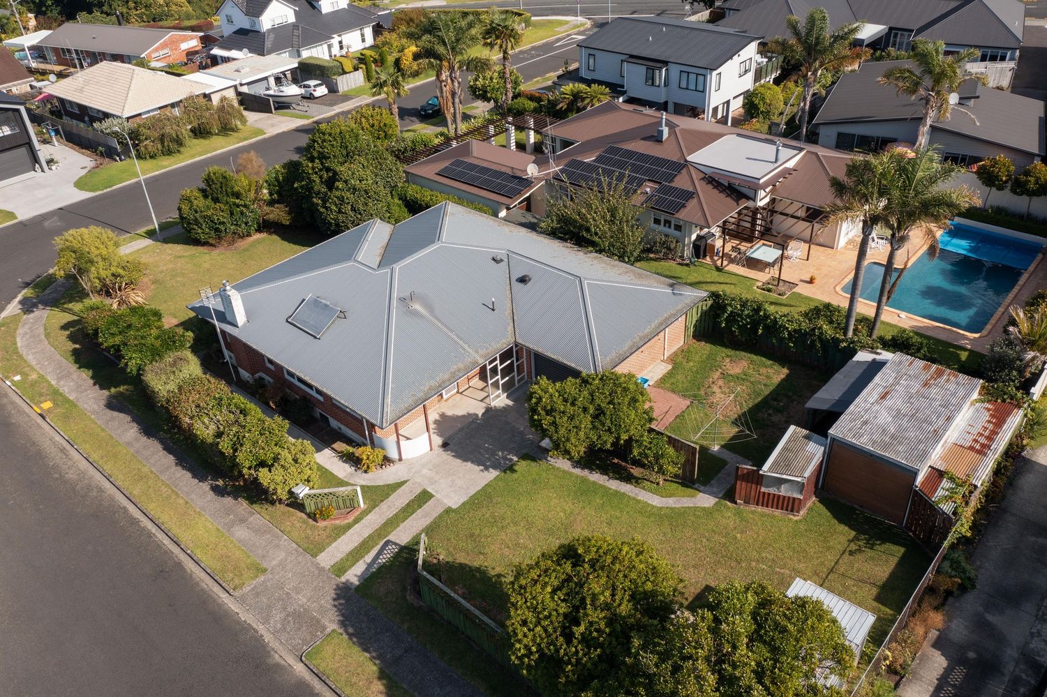 Drone shot of residential area showing modern houses with pools and well-maintained yards in a suburban setting.