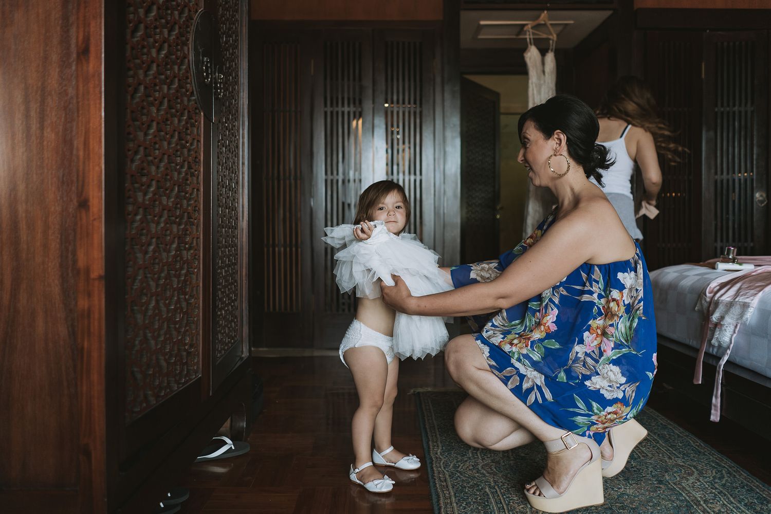 Parent and child share a playful moment in traditional dress during preparations.