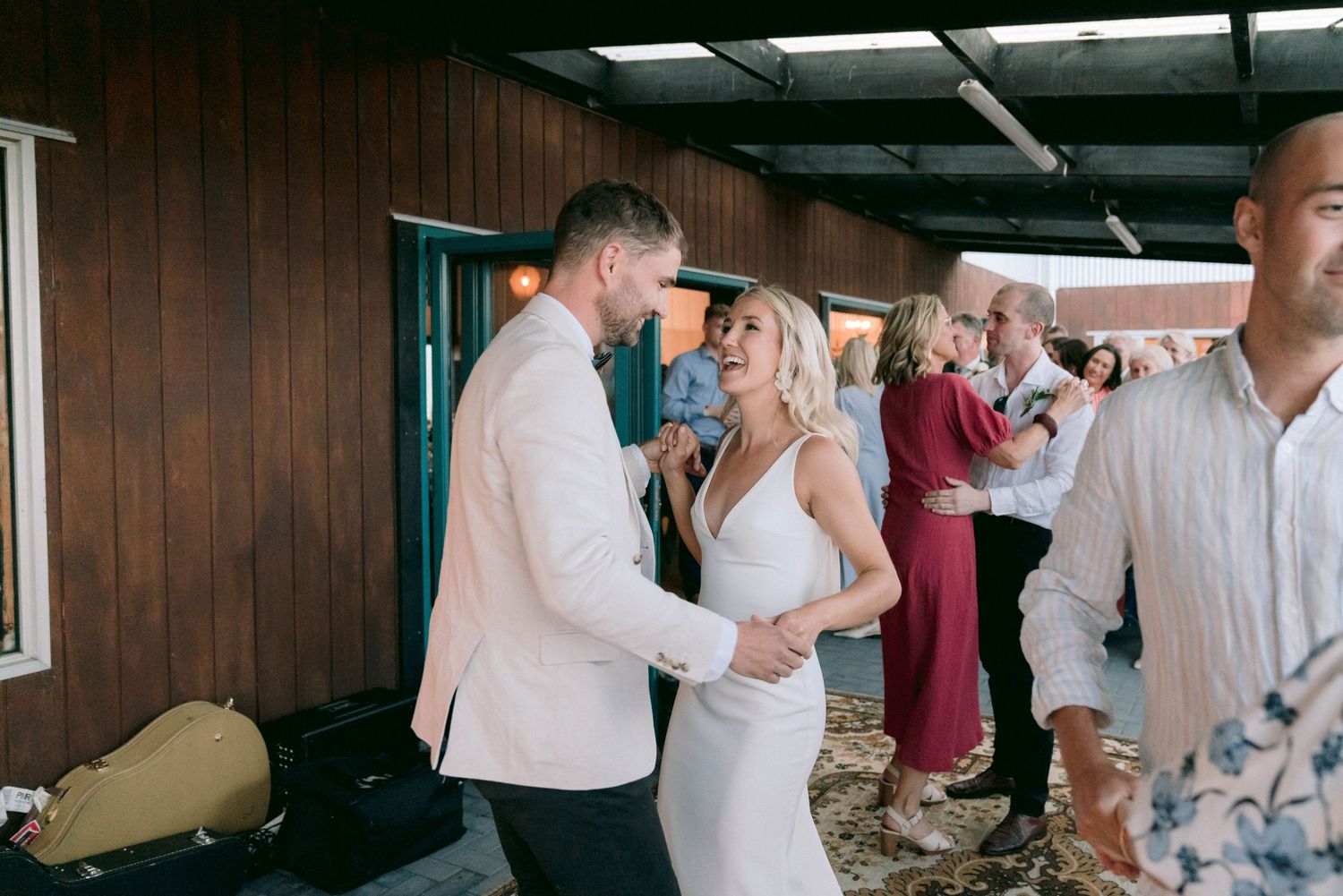 Wedding celebration inside rustic venue with dancing and festivities.