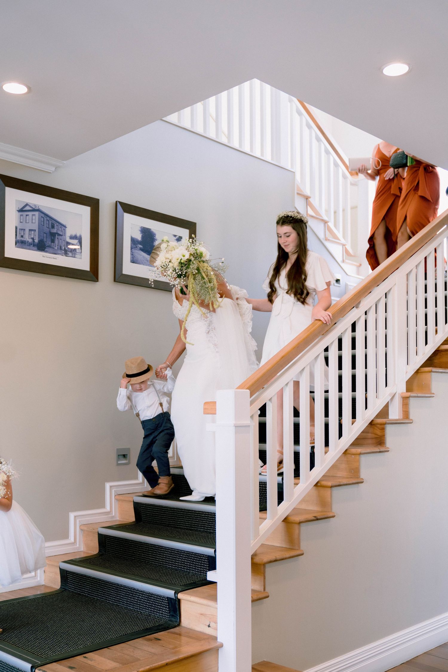 Interior staircase with white spindle railings and wooden steps featuring dark carpet runner leads upstairs.