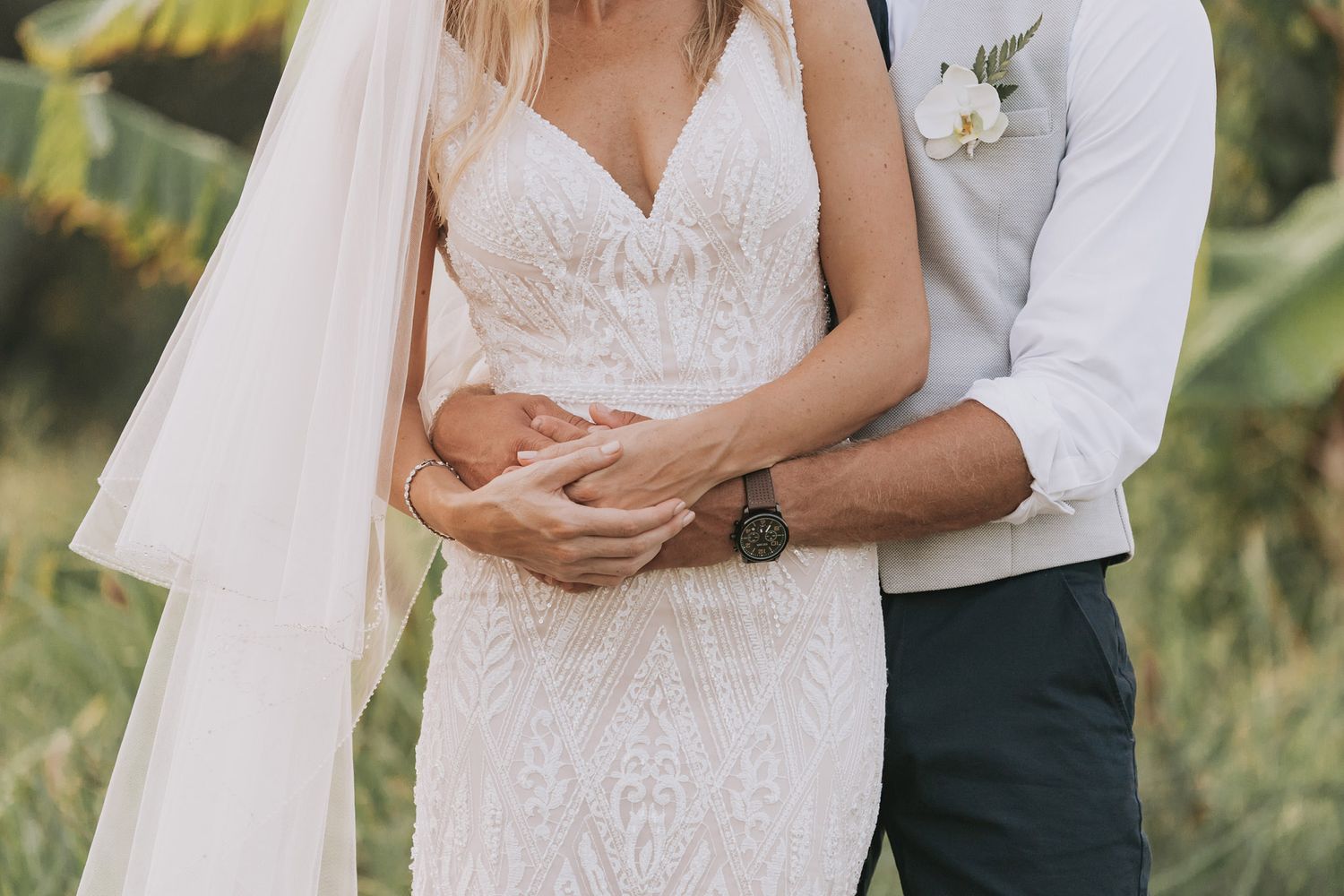 Elegant bridal details showing lace wedding dress and floral accents in natural lighting.
