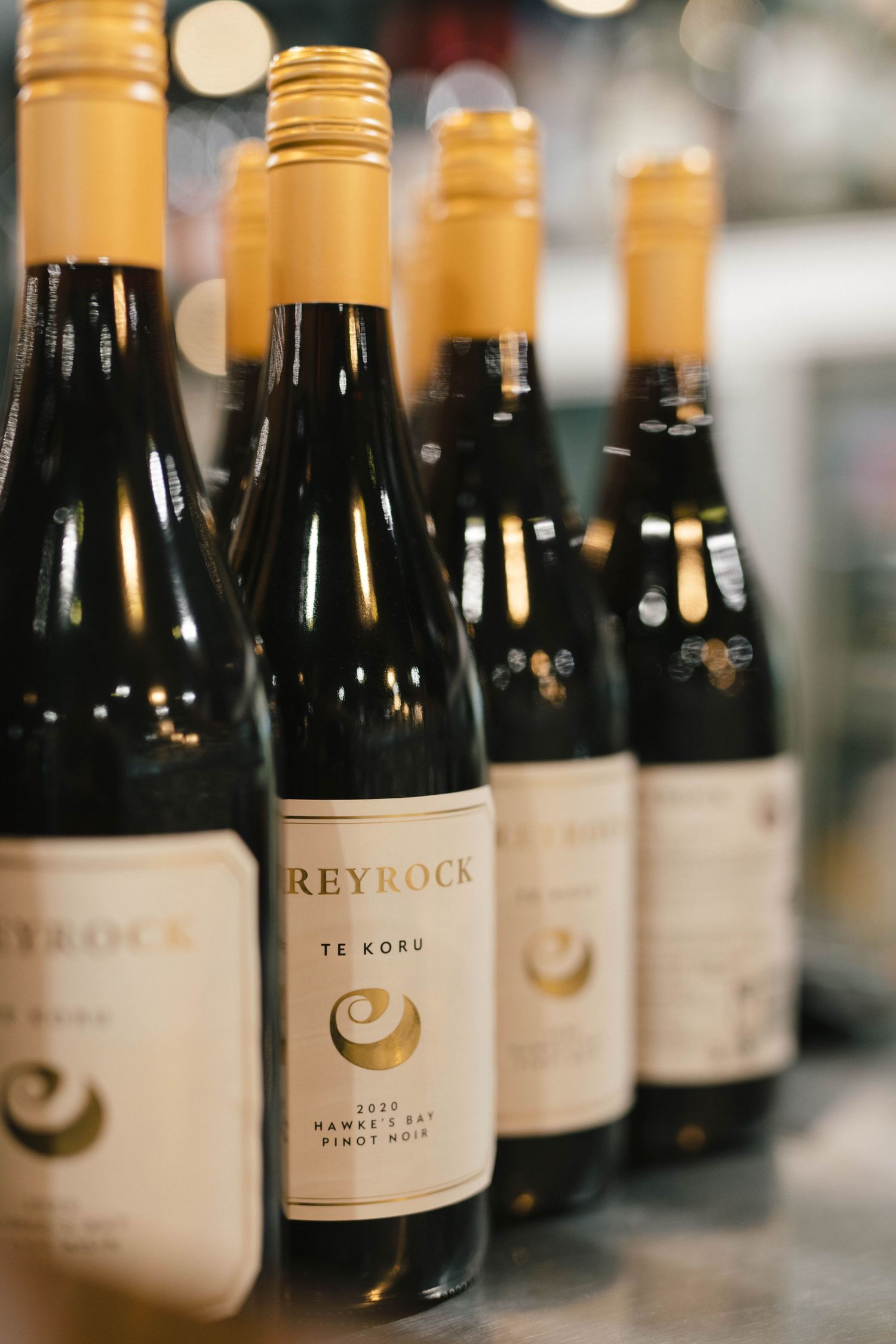Row of wine bottles from Greyrock winery displayed on a shelf with elegant white labels.