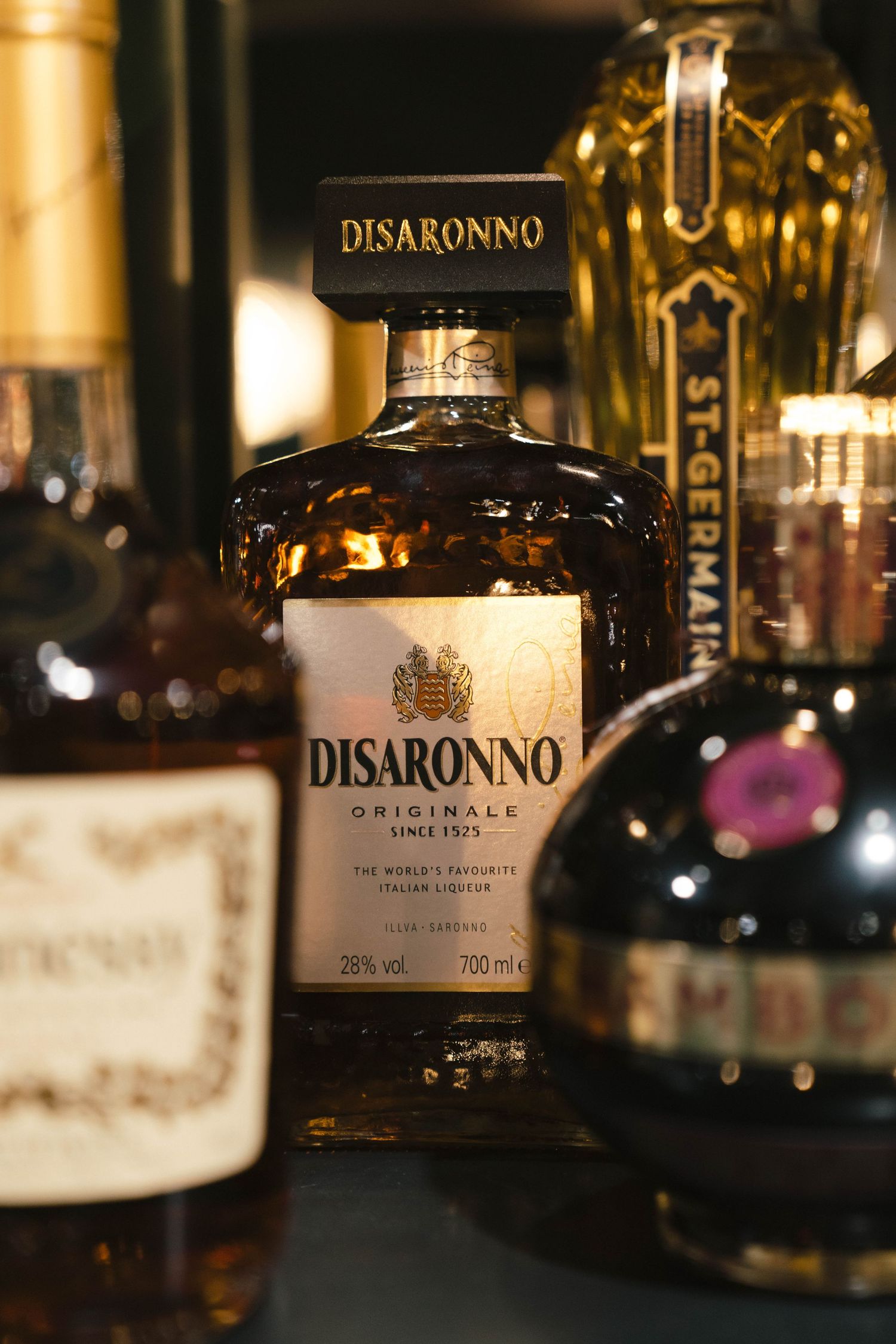 Close-up of Disaronno liquor bottles on display in dark ambient lighting.