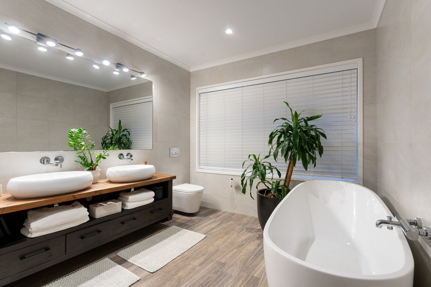Luxurious bathroom features freestanding tub, wood vanity, and sleek fixtures in a minimalist design.
