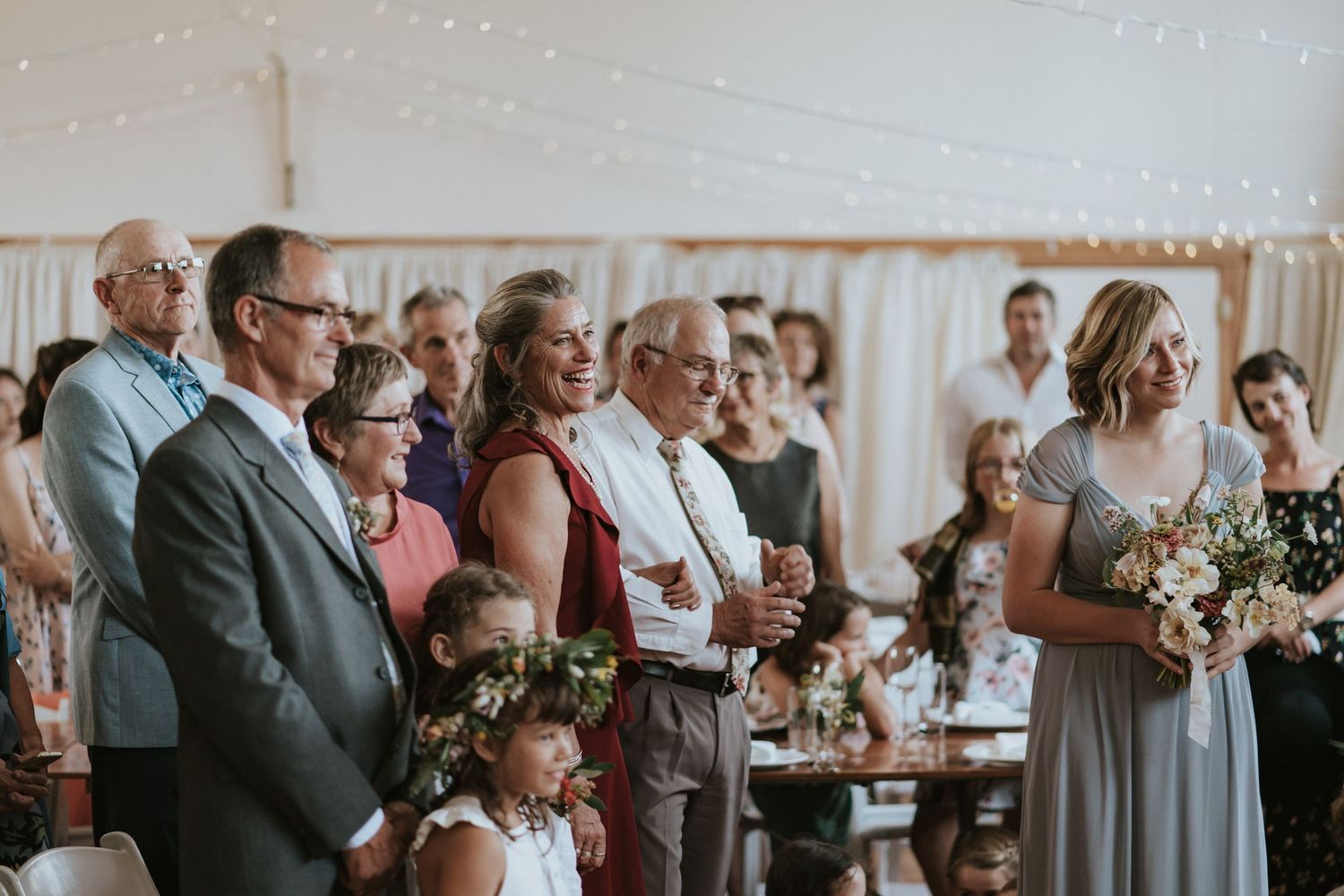 Wedding guests celebrating with raised glasses during an indoor reception at an elegant venue.